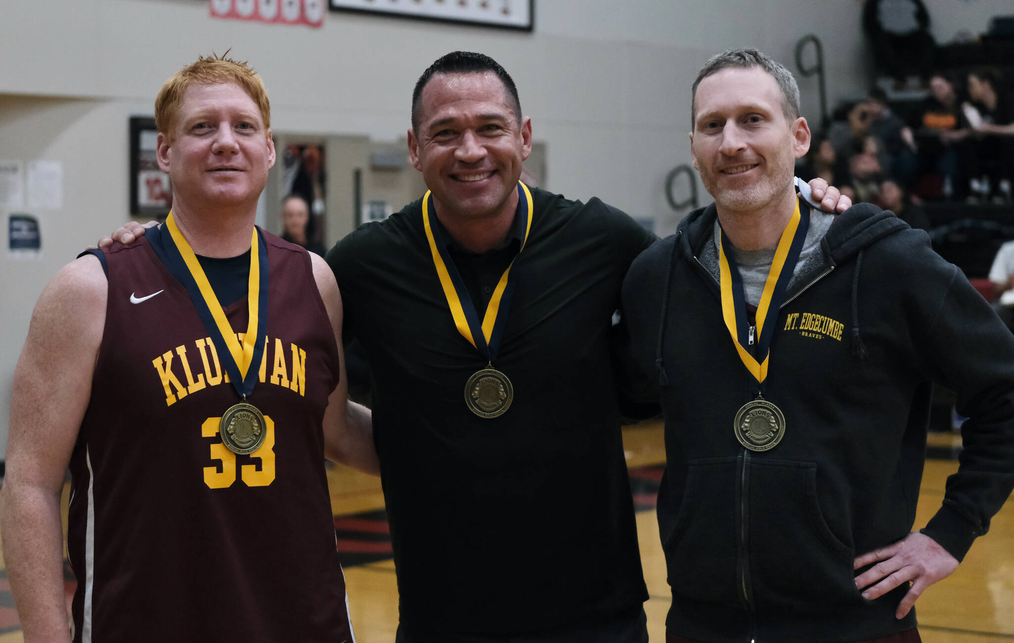 Jesse McGraw, Matt Carle and Andrew Friske pose for a photo after their induction into the Gold Medal Hall of Fame, Friday, March 24, during the Juneau Lions Club 74th Annual Gold Medal Basketball Tournament at the Juneau-Douglas High School: Yadaa.at Kalé gymnasium. (Klas Stolpe/For the Juneau Empire)