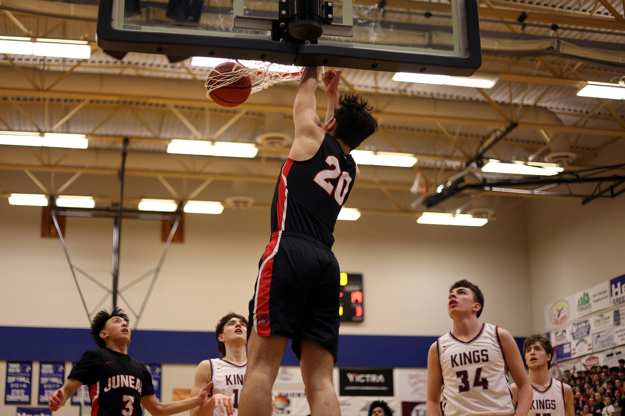 JDHS senior Orion Dybdahl finishes a dunk with authority as teammate Alwen Carrillo (3) and Kayhi’s, Marcus Stockhausen (34) and Andrew Kleinschmidt (13) look on. Dybdahl earned third team all-state honors with his play this season. (Ben Hohenstatt / Juneau Empire)