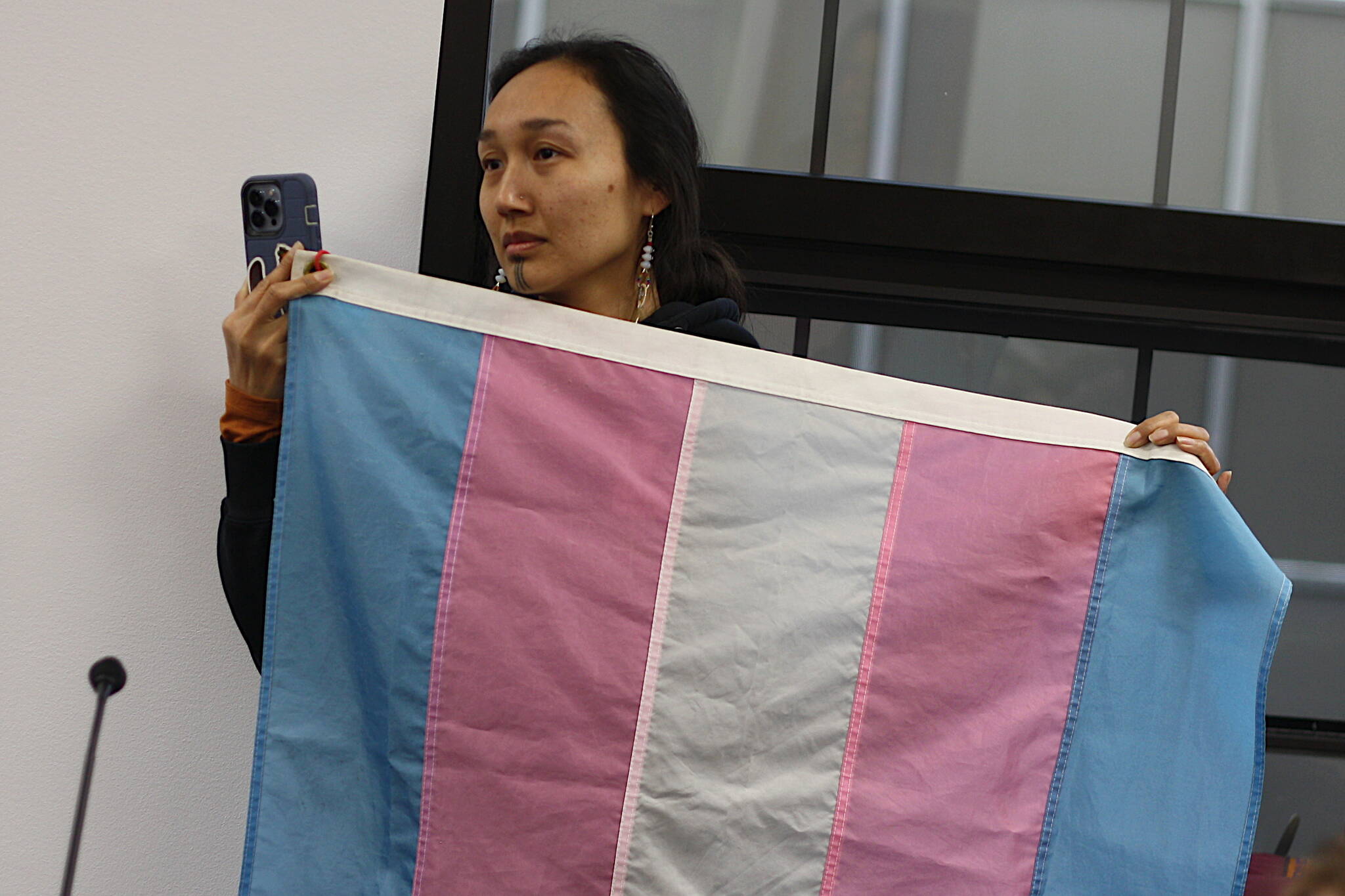 Mark Sabbatini / Juneau Empire 
Charlene Apok, director of gender justice and healing at Native Movement, holds up a transgender flag during public testimony on a bill limited sex and gender content in schools Thursday night at the Alaska State Capitol.