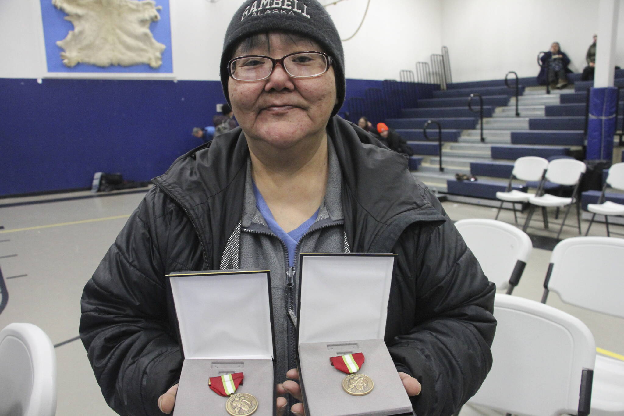 This March 28, 2023, photo shows JoAnn Kulukhon posing with two Alaska Heroism Medals presented posthumously to her uncles, Pvts. Luke and Leroy Kulukhon, during a ceremony in Gambell, Alaska. Sixteen Alaska National Guard members were honored for helping rescue the 11 crewmembers of a Navy plane that was shot down in 1955 by Soviet jet fighters and crash-landed about 8 miles from Gambell, on St. Lawrence Island, and 15 medals were presented posthumously. (AP Photo / Mark Thiessen)