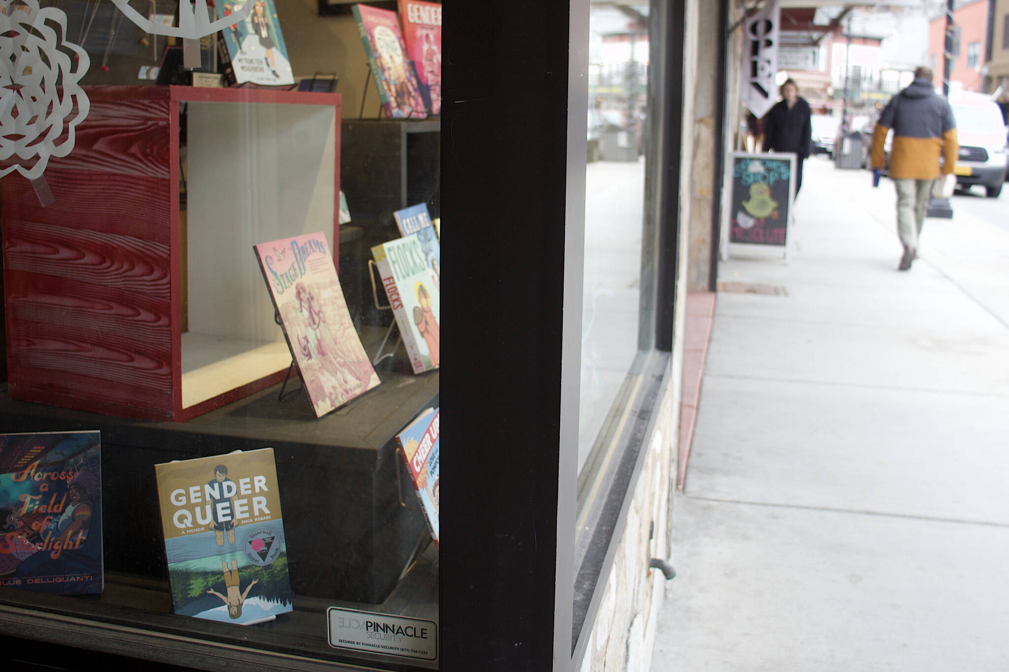 A collection of books including LGBTQ-friendly titles are displayed in the storefront window of Alaska Robotics in downtown Juneau on Tuesday. The store, which featured books and cards illustrated by local artist Mitchell Watley, removed them following his arrest Sunday for allegedly placing transphobic notes threatening violence against children at locations around town. (Mark Sabbatini / Juneau Empire)