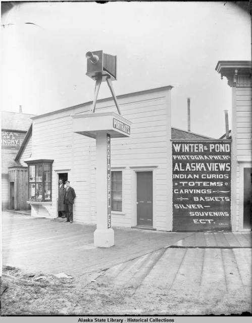 Famous Juneau photographers Lloyd Winter and Percy Pond stand in front of their studio located at the corner of Front and Franklin Streets in about 1900. Their photos document Juneau’s history and were originally taken on glass plates. (Alaska State Library, P87-0981)