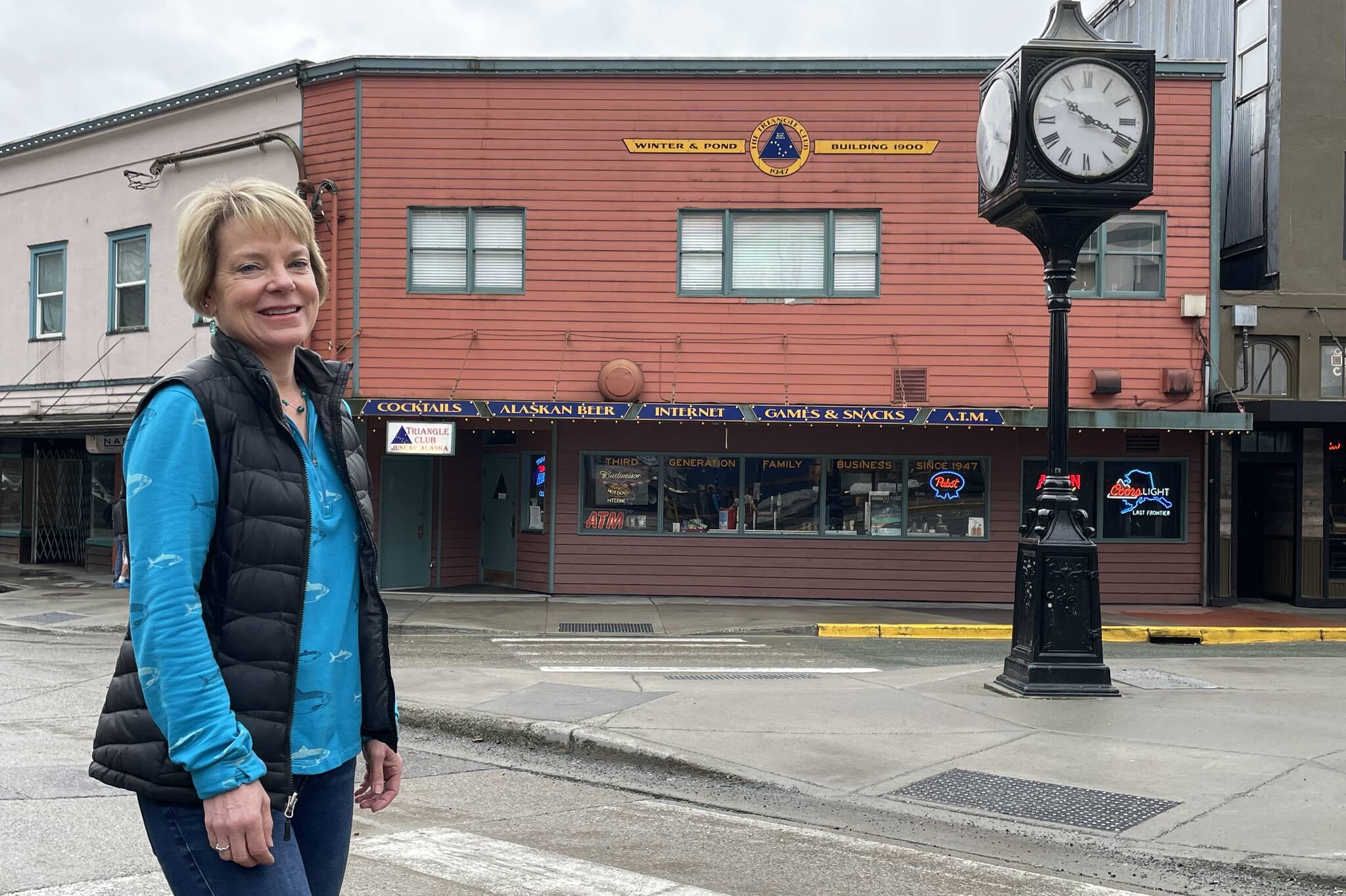 Leeann Thomas, third-generation owner of the Triangle Club, stands before the business her grandfather started in 1947. The location has a long history of Juneau businesses. (Laurie Craig / For the Downtown Business Association)