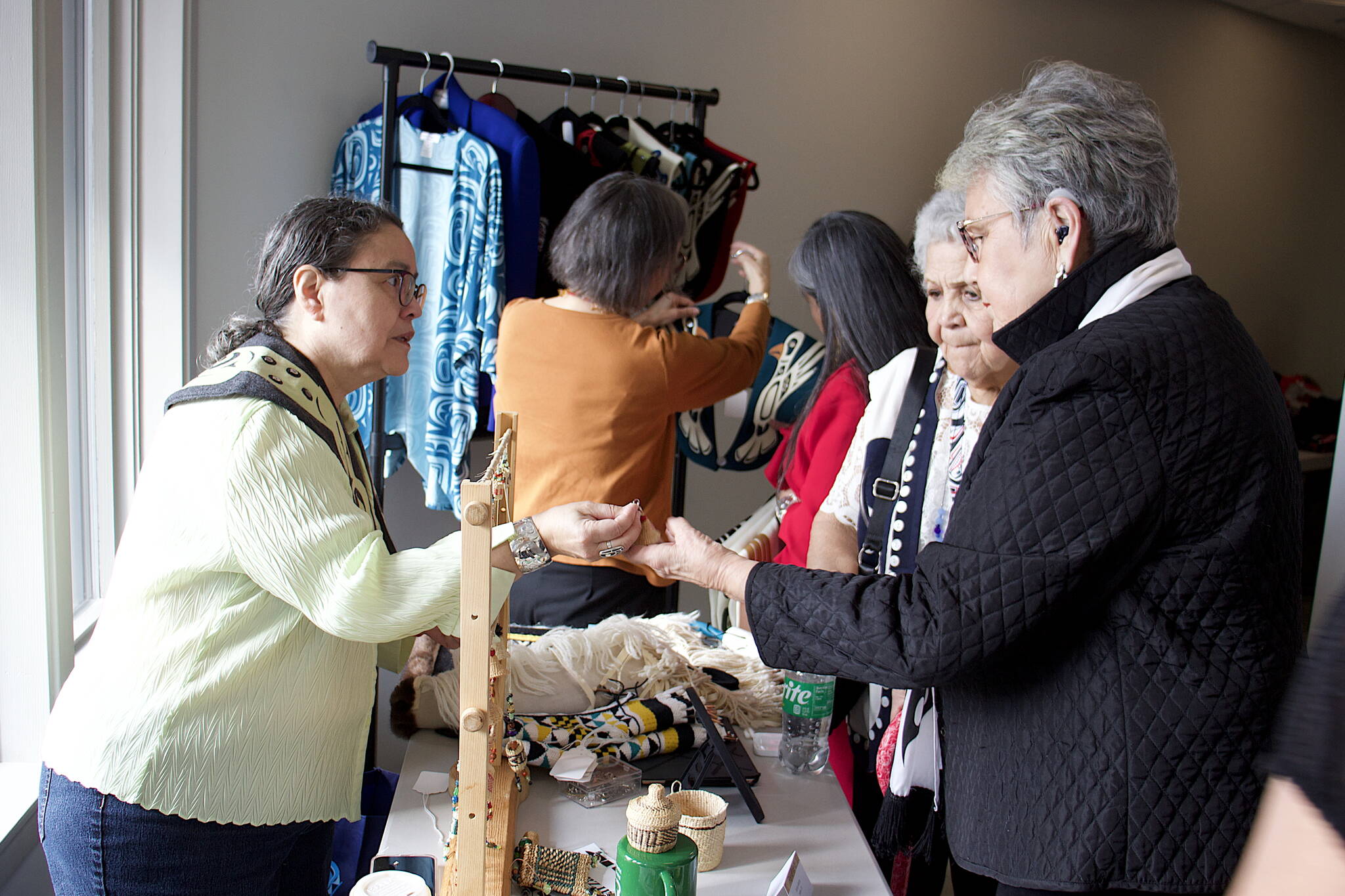 Dolly Garza, a former Ketchikan resident now living in Haida Gwaii, Canada, shows her handmade crafts to delegates Wednesday morning in a hallway at Elizabeth Peratrovich Hall during the 88th annual tribal assembly of the Central Council of the Tlingit and Haida Indian Tribes of Alaska. (Mark Sabbatini / Juneau Empire)