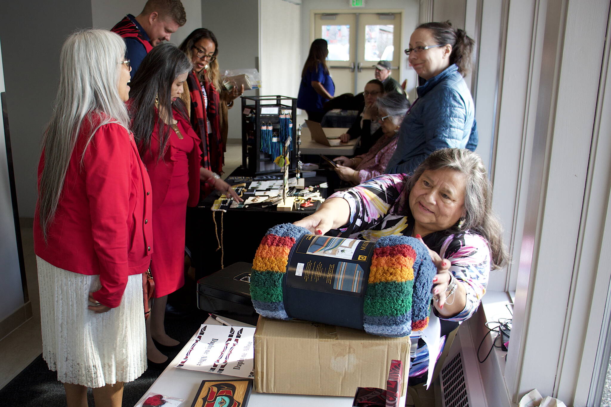 Cindy Pederson, sets up a display table for raffle items in a hallway at Elizabeth Peratrovich Hall during the 88th annual Tribal Assembly of the Central Council of the Tlingit and Haida Indian Tribes of Alaska. Pederson, a Seattle resident and delegate for nearly 20 years until taking a job with the tribe’s COVID-19 relief program last year, was named the tribe’s Delegate/Citizen of the Year on Thursday. (Mark Sabbatini / Juneau Empire)