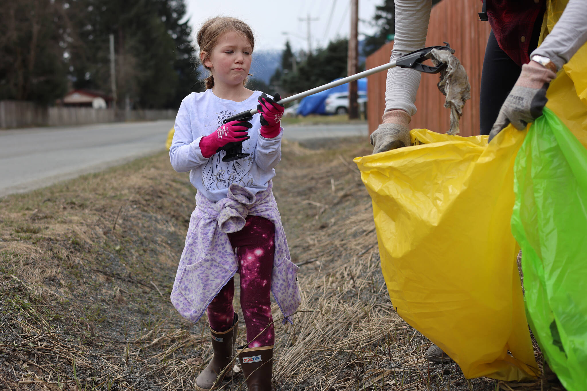 Catherine Berry, 6, places litter in a bag held open by her mother, Mary, during a communitywide cleanup held on Earth Day. The cleanup of public lands is an annual event organized by Litter Free Inc. (Ben Hohenstatt / Juneau Empire)