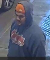 The Juneau Police Department is asking the community to assist in identifying a man who allegedly threw a large rock at a police patrol vehicle windshield at around 2:30 a.m. on April 16. This is a picture shared by police of the the man wearing an orange cap and gray hoody as seen in surveillance footage. (Juneau Police Department)