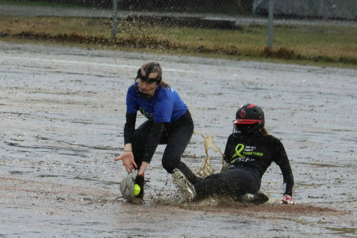 JDHS’ Gloria Bixby slides safe into second base and under the tag of TMHS’ Jenna Dobson during the first inning of a drizzly Friday night game against Thunder Mountain High School in May 2021 that raised money for mental health. TMHS and JDHS both will be participating in the Paint it Pink Cancer Awareness games on Saturday, May 13 along with Ketchikan and Sitka high schools at Melvin Park and Dimond Park Field No. 4 (Ben Hohenstatt / Juneau Empire File)
