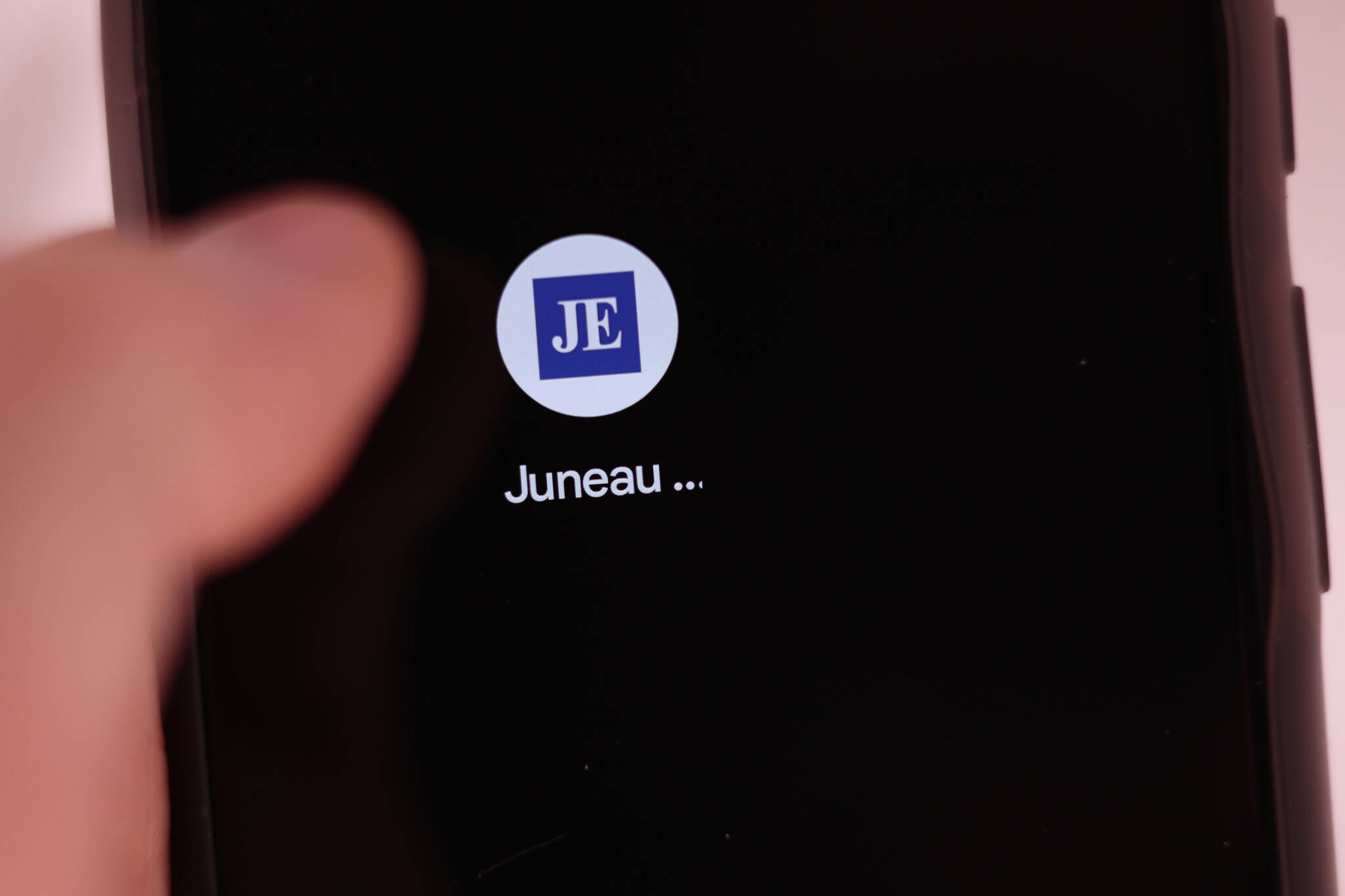 A thumb hovers over a smartphone screen displaying the Juneau Empire app. While many people read the Empire on their phones or tablets today, that option didn’t exist in 1996 when the Empire first went digital. (Ben Hohenstatt / Juneau Empire)