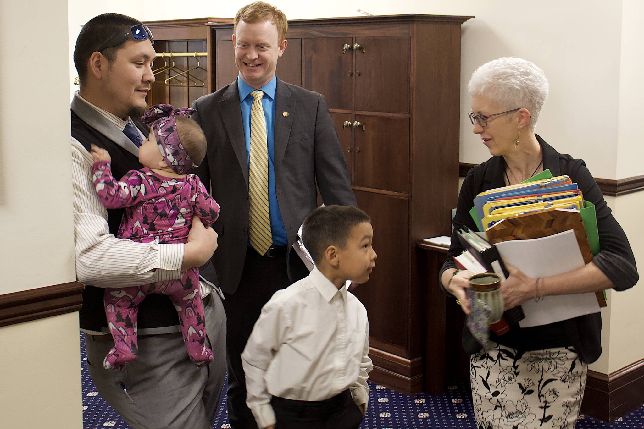 State Rep. Josiah Patkotak, I-Utqiagvik, left, holds his daughter, Francine Jo, seven months old, while his son, Dillion, 7, greets Chief House Clerk Crys Jones and Rep. David Eastman, R-Wasilla, looks on before the start of the House floor session Saturday. It is the first weekend floor session this year for both the House and Senate as they try to conclude their legislative business before their scheduled adjournment Wednesday. (Mark Sabbatini / Juneau Empire)