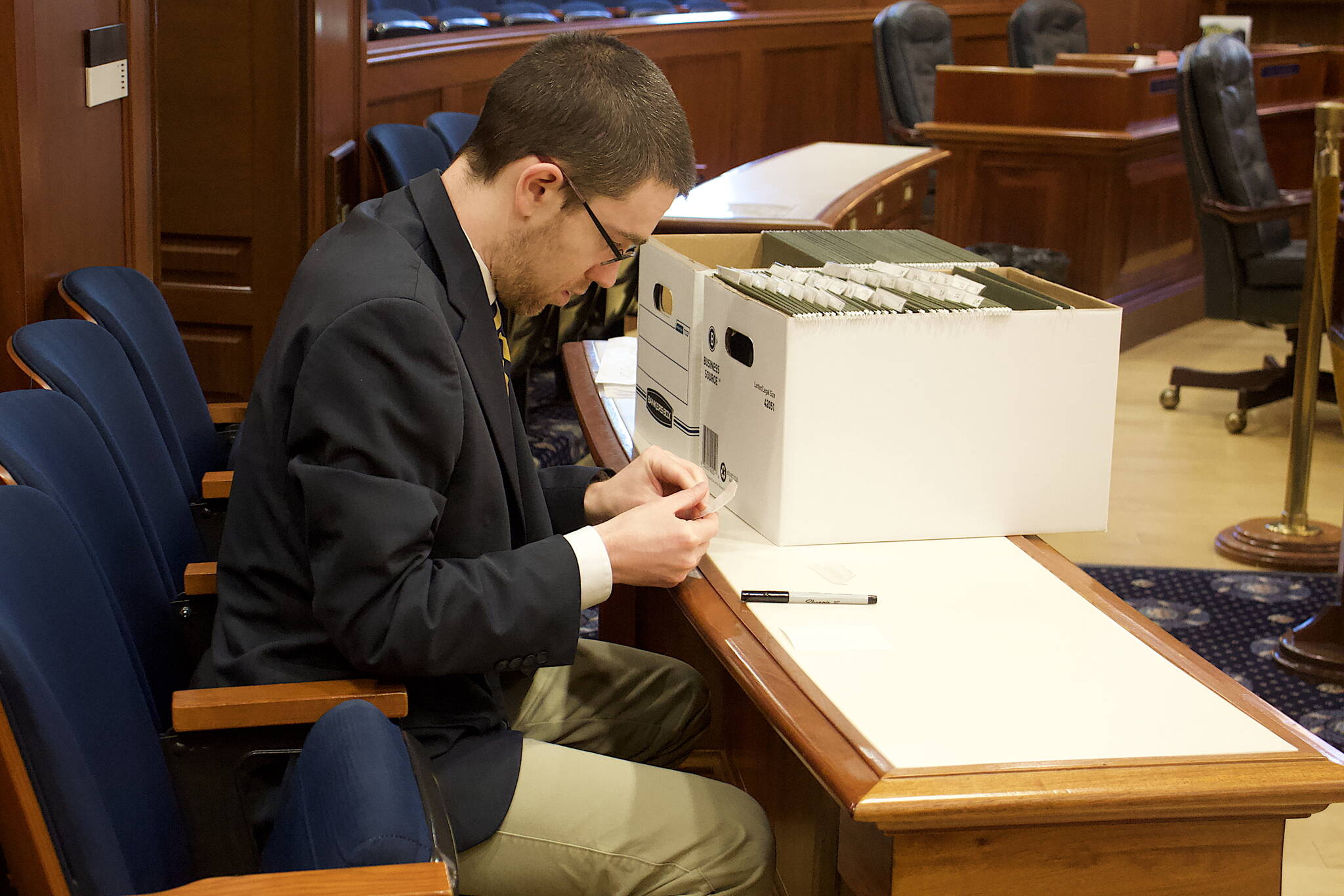 Ryan Rivers, a state Senate page, prepares file folders for proposed amendments to the state budget bill the Senate is scheduled to consider during its floor session Monday. (Mark Sabbatini / Juneau Empire)