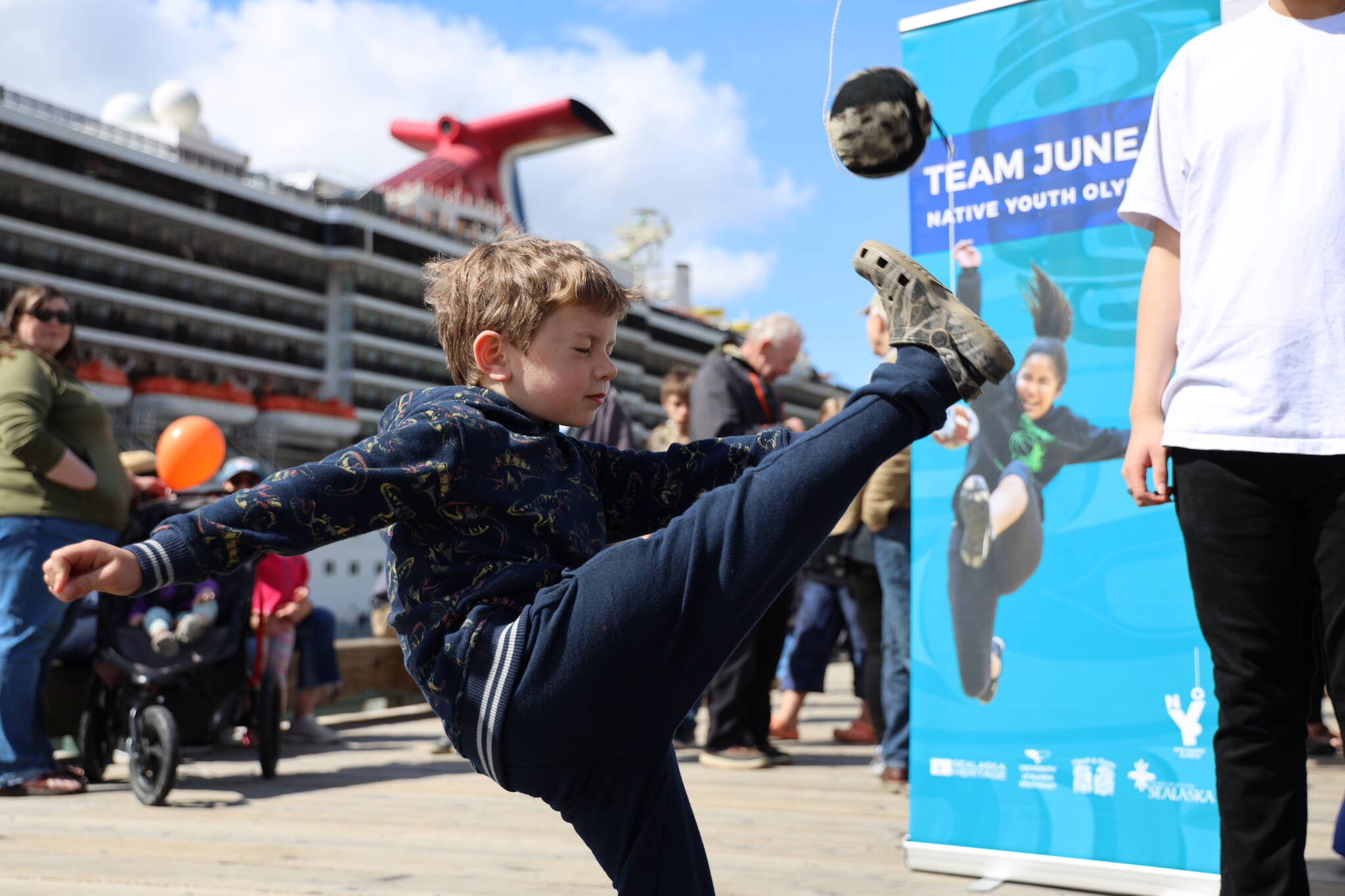 Garrison McNeill, 5, kicks high as he attempts the one-foot high kick at a booth hosted by the Team Juneau Native Group Olympics team. Coach Matthew Quinto said the group’s booth was set up to invite youth to try out the sport and learn more about the team. (Clarise Larson / Juneau Empire)
