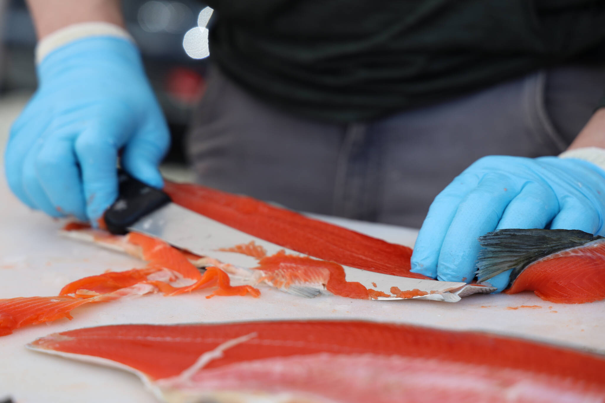 Jared Jerabek with Alaska Glacier Seafood fillets sockeye salmon to be cooked and handed out for free by Taku Smokeries during 2023 Juneau Maritime Festival Saturday afternoon at the Elizabeth Peratrovich Plaza. (Clarise Larson / Juneau Empire)