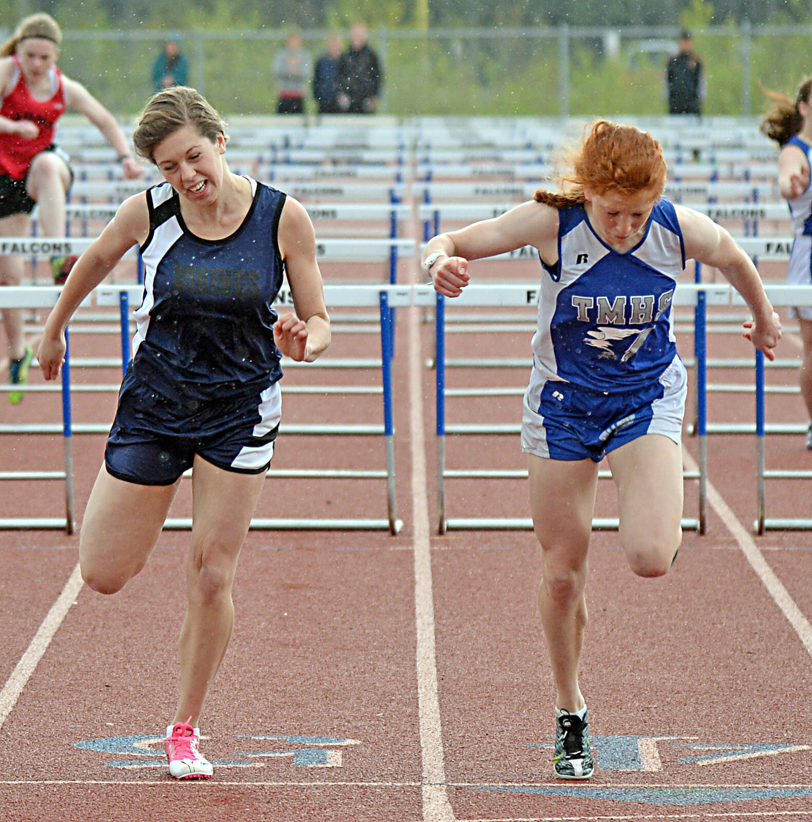 Petersburg High School sophomore Izabelle Ith, left, and Thunder Mountain junior Naomi Welling lean into the finish of the girls 100-meter hurdles finals at the 2015 Capital City Invitational. (Klas Stolpe / Juneau Empire)