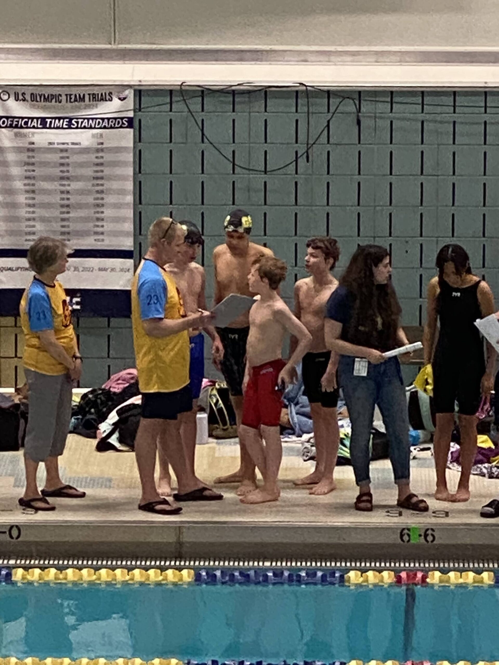 Glacier Swim Club swimmers Liam Kiessling, Sam Pallenberg, Andrew Sanders and Josh Edwards speaking to head coach Scott Griffith after the at the boys ages 13-14 relay race at this year’s Alaska Swimming State Championship in Anchorage. (Courtesy Photo / Savona Kiessling)