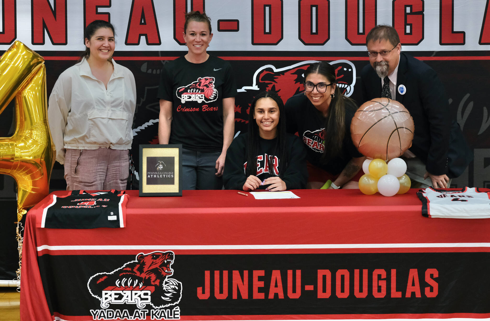 JDHS assistant coach Jasmine James, JDHS head coach Tanya Nizich, JDHS senior Kiyara Miller, JDHS assistant coach Nicole Fenumiai and retired JDHS coach Steve Potter on Wednesday in the JDHS gymnasium after Miller signed a letter of intent to play basketball at Peninsula College. (Klas Stolpe / Juneau Empire)