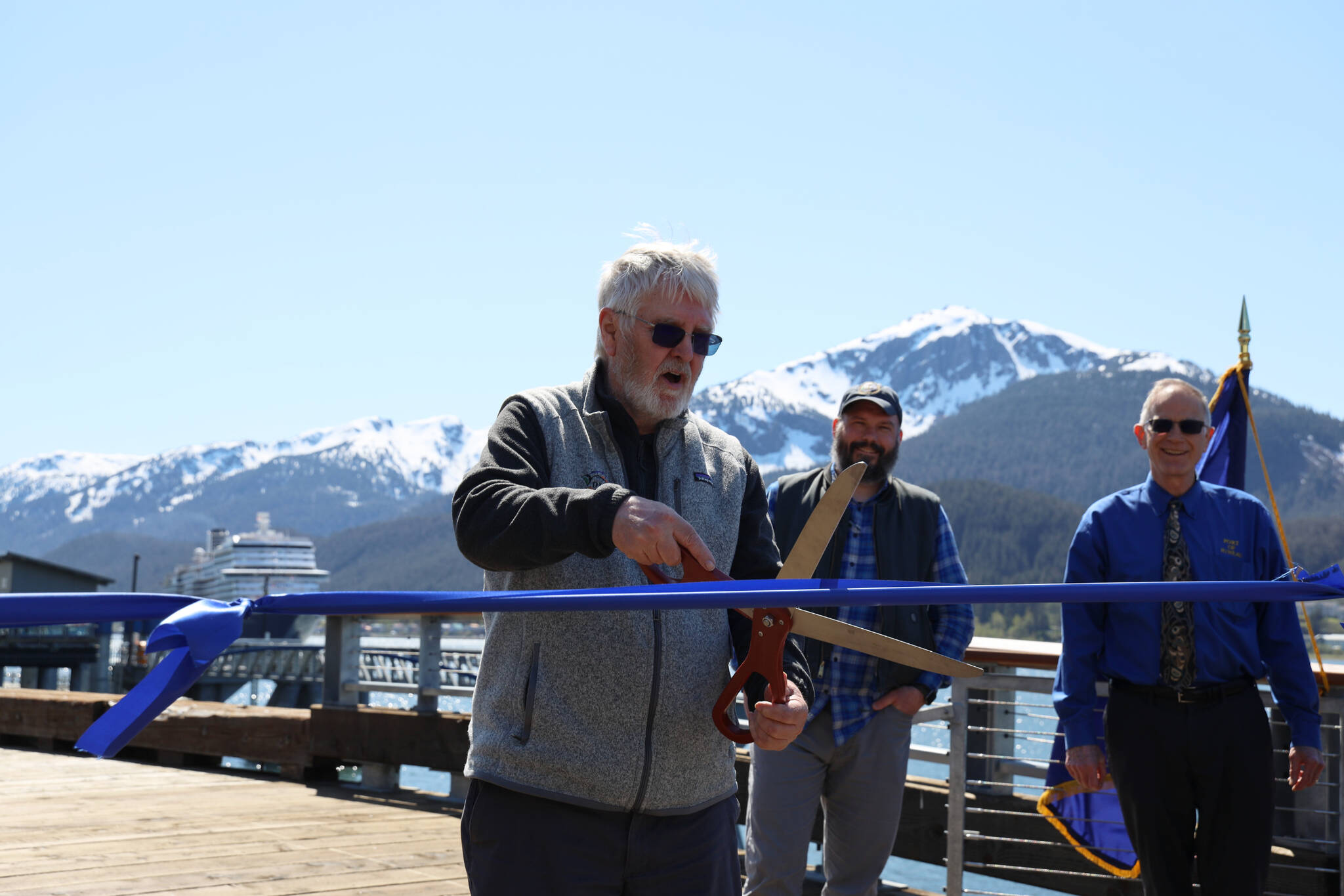 City and Borough of Juneau Docks and Harbors Board Vice Chairman Jim Becker cuts a ribbon Monday afternoon stretched across the Seawalk downtown in celebration of the city’s completion of the Docks and Harbors Marine Deckover Project. (Clarise Larson / Juneau Empire)