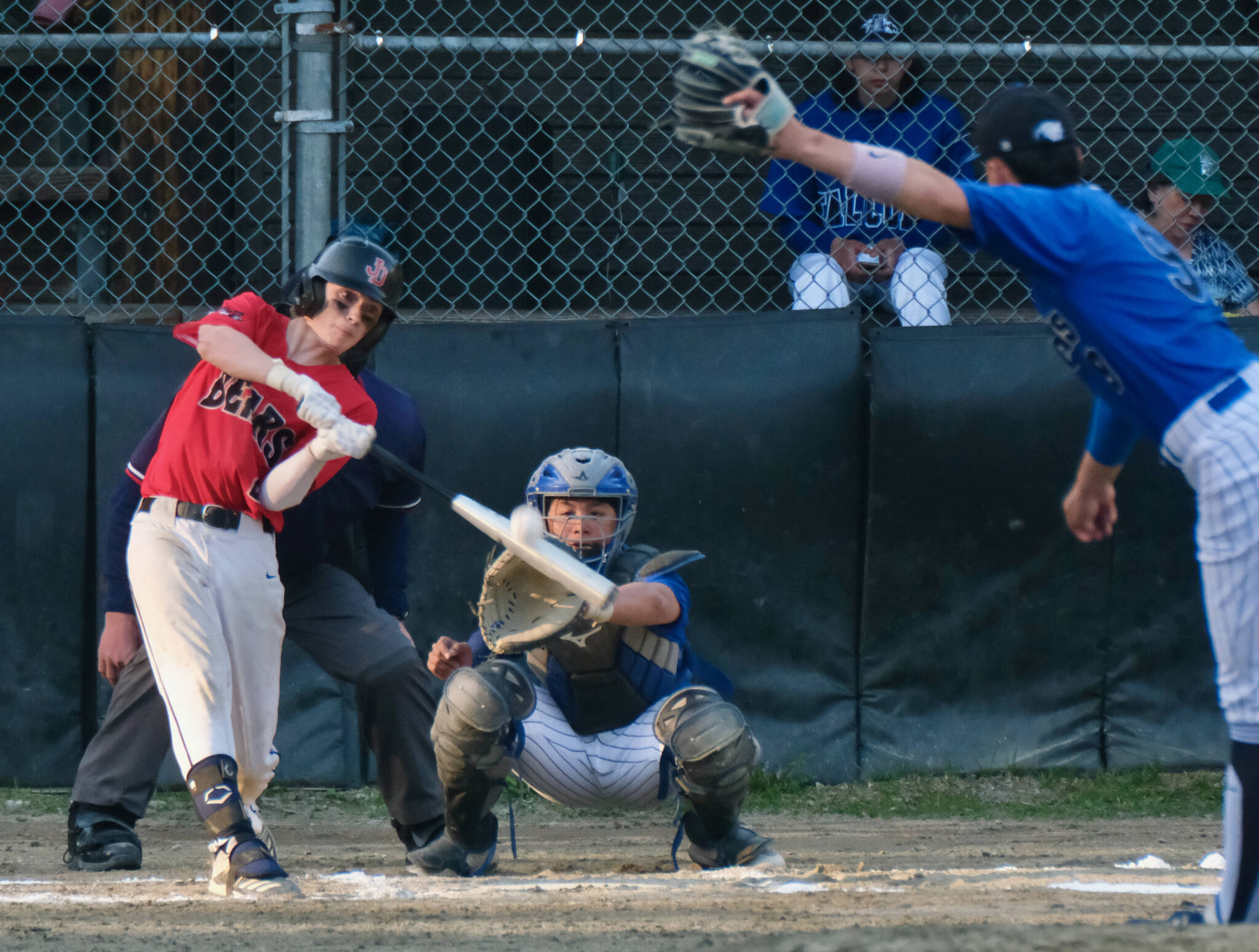Juneau-Douglas High School: Yadaa.at Kalé Crimson Bears batter Bodhi Nelson connects on a pitch from Thunder Mountain Falcons pitcher Rory Hayes as catcher JJ McCormick looks on Wednesday at Adair-Kennedy Field. (Klas Stolpe / Juneau Empire)