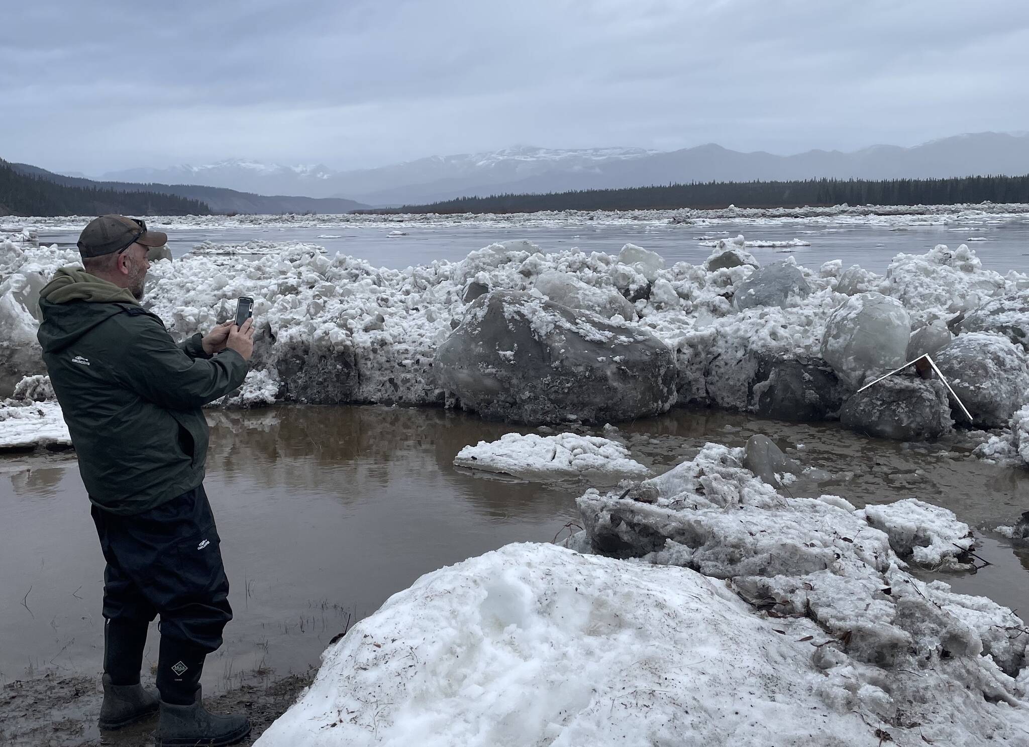 2. Ryan Becker, a teacher at the Eagle school, takes a photo of the toppled Front/Lincoln Street sign after Yukon River ice overtopped the town’s seawall on the morning of May 13, 2023. Photo by Ned Rozell.