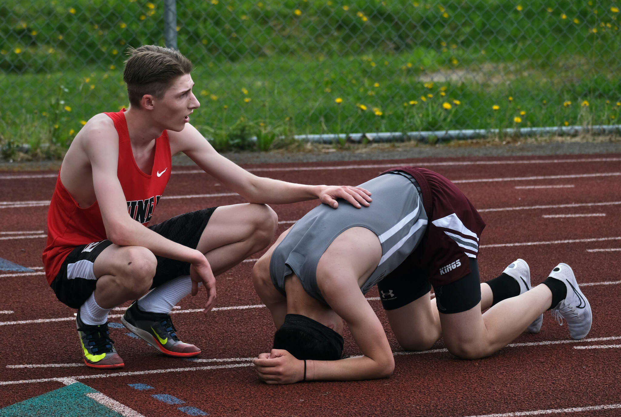 JDHS sophomore Joshua Reed supports Ketchikan freshman Carter Phillips at the finish of the combined DI/DII 3200 meters during the Region V Track & Field Championships, Friday, at Thunder Mountain. The championships resume Saturday. (Klas Stolpe / Juneau Empire)