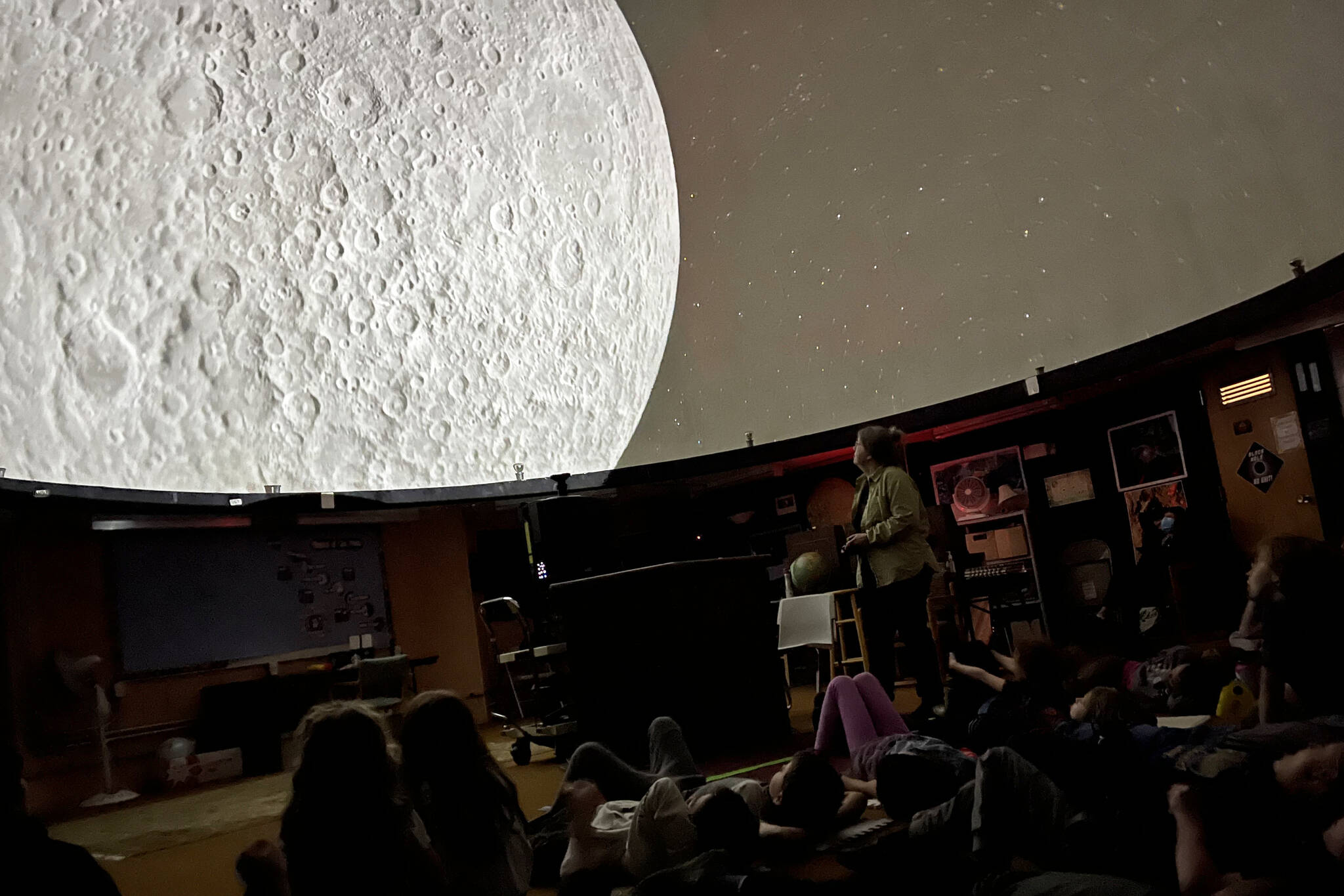 Rosemary Walling shows Montessori Borealis students close up views of the moon in between recorded segments of the story of Raven and the Box of Daylight on Friday as part of the Marie Drake Planetarium’s student field trips made possible by a grant from Douglas Dornan Foundation. (Jonson Kuhn / Juneau Empire)