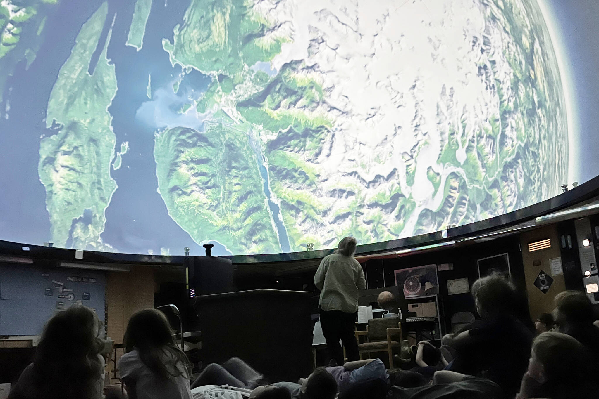 Volunteer Educator Rosemary Walling shows a group of Montessori Borealis first through third graders images of the Earth on Friday at the Marie Drake Planetarium as part of a special presentation of the story of Raven and the Box of Daylight. (Jonson Kuhn / Juneau Empire)