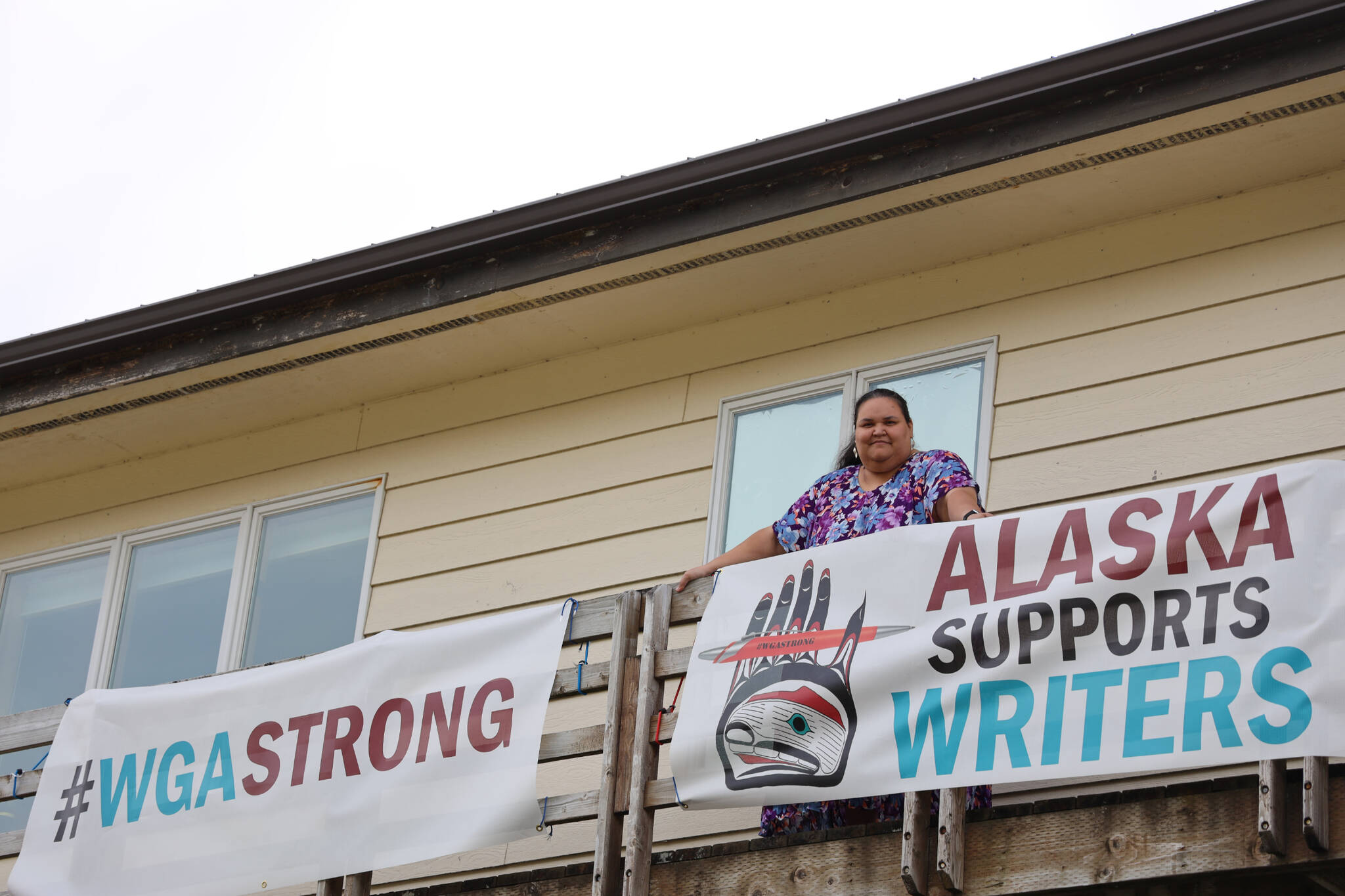 Award-winning Juneau writer Vera Starbard stands on her balcony on Douglas Island that displays banners across Gastineau Channel in support of the Writer’s Guild of America union strike currently going on across Hollywood and the country. (Clarise Larson / Juneau Empire)