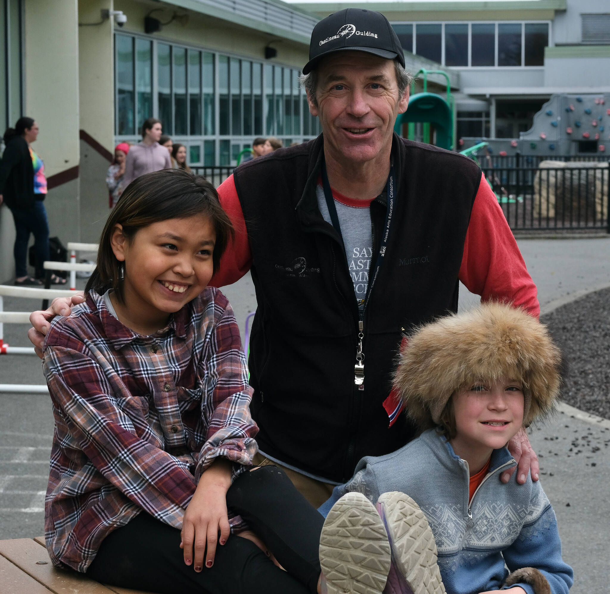Sayéik: Gastineau Community School physical education teacher Dirk Miller poses with Nevaea Johnson and Nolan Seris during a Field Day break at the school Thursday. Miller is retiring after 24 years at the school. (Klas Stolpe / Juneau Empire)