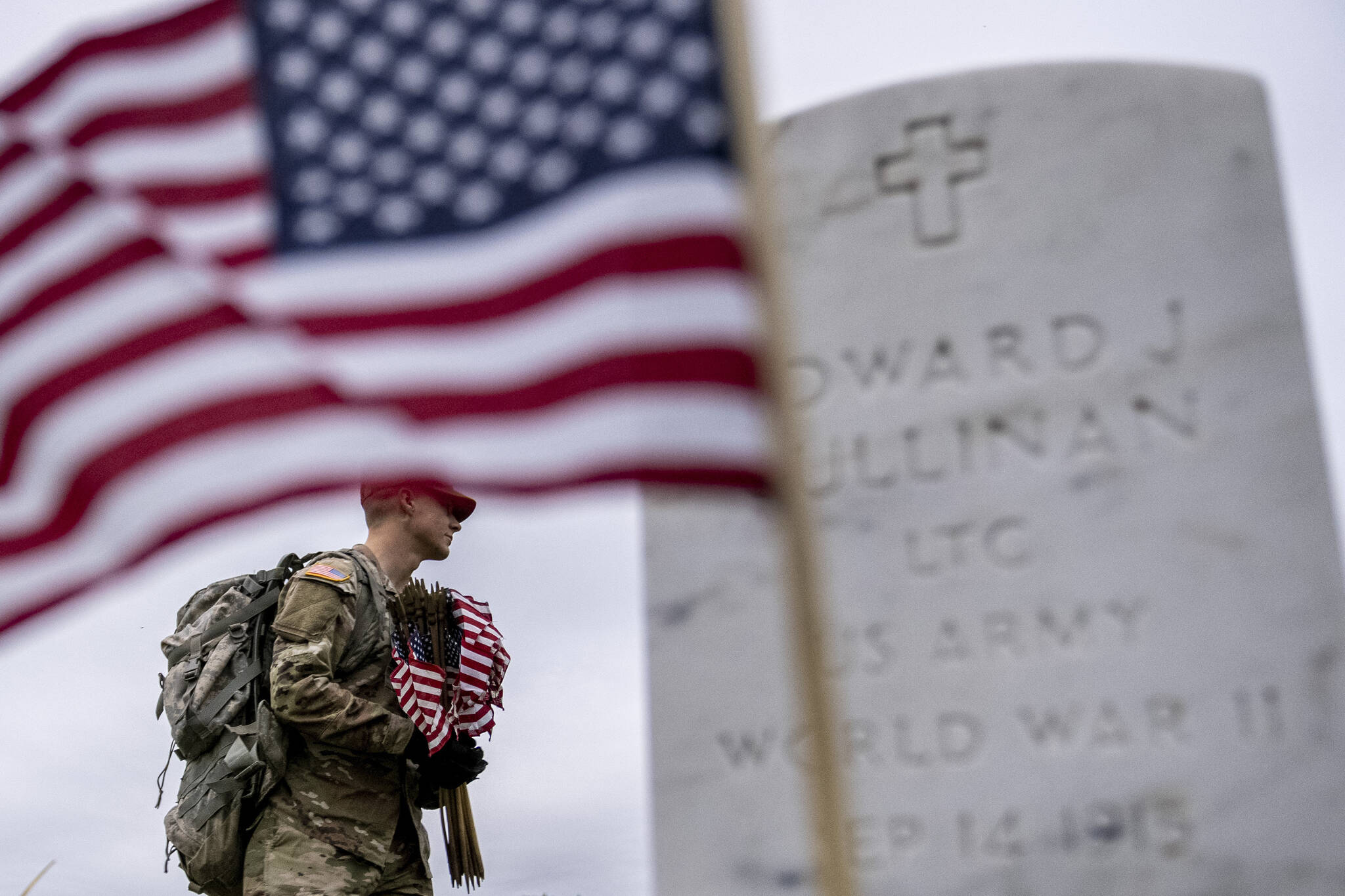 A member of the 3rd U.S. Infantry Regiment, also known as The Old Guard, places flags in front of each headstone for “Flags-In” at Arlington National Cemetery in Arlington, Thursday, May 25, 2023, to honor the Nation’s fallen military heroes ahead of Memorial Day. (AP Photo / Andrew Harnik)
