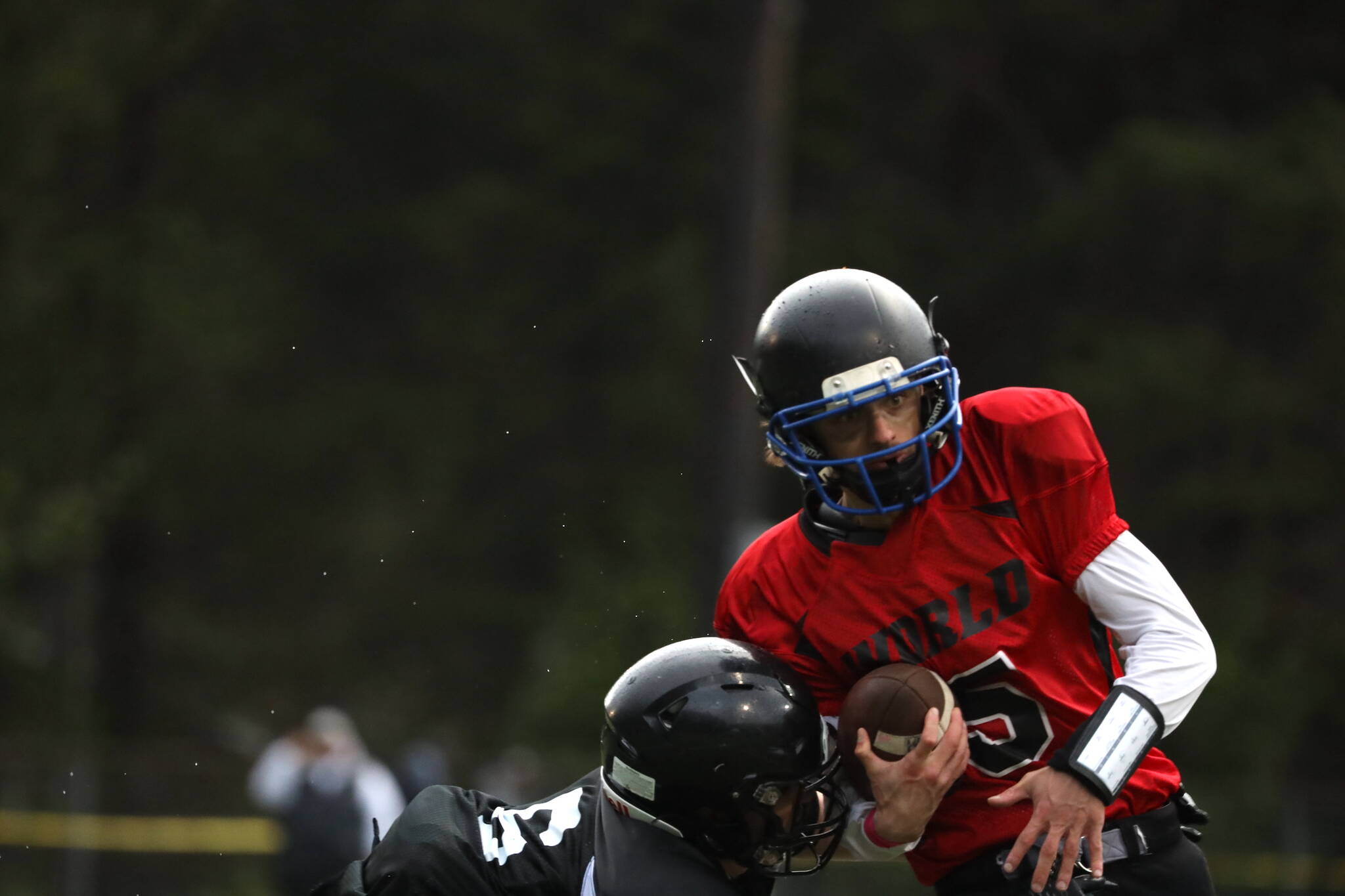 Team World player and 2018 Thunder Mountain High School graduate Jacob Tapia holds tight to the ball while running down the field during the Juneau Alumni Football game on Friday at Adair-Kennedy Memorial Park. (Clarise Larson / Juneau Empire)
