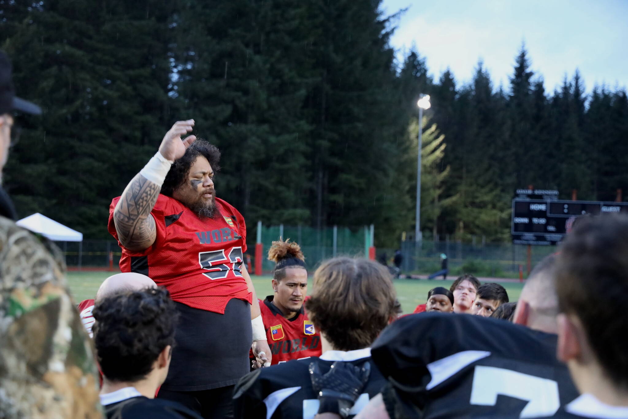 Team World coach and player Lino Fenumiai says a prayer over both teams after the Juneau Alumni Football game Friday evening at Adair-Kennedy Field. (Clarise Larson / Juneau Empire)