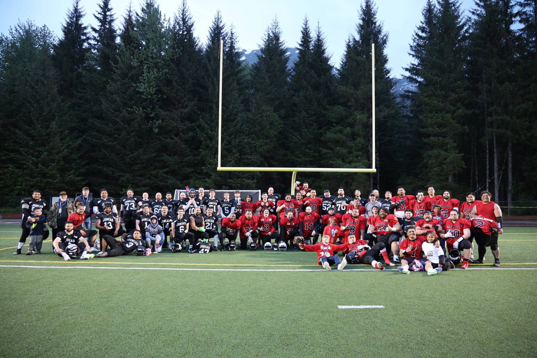 Team World and Team Juneau join together for a photo after the Juneau Alumni Football game Friday evening at Adair-Kennedy Field. (Clarise Larson / Juneau Empire)