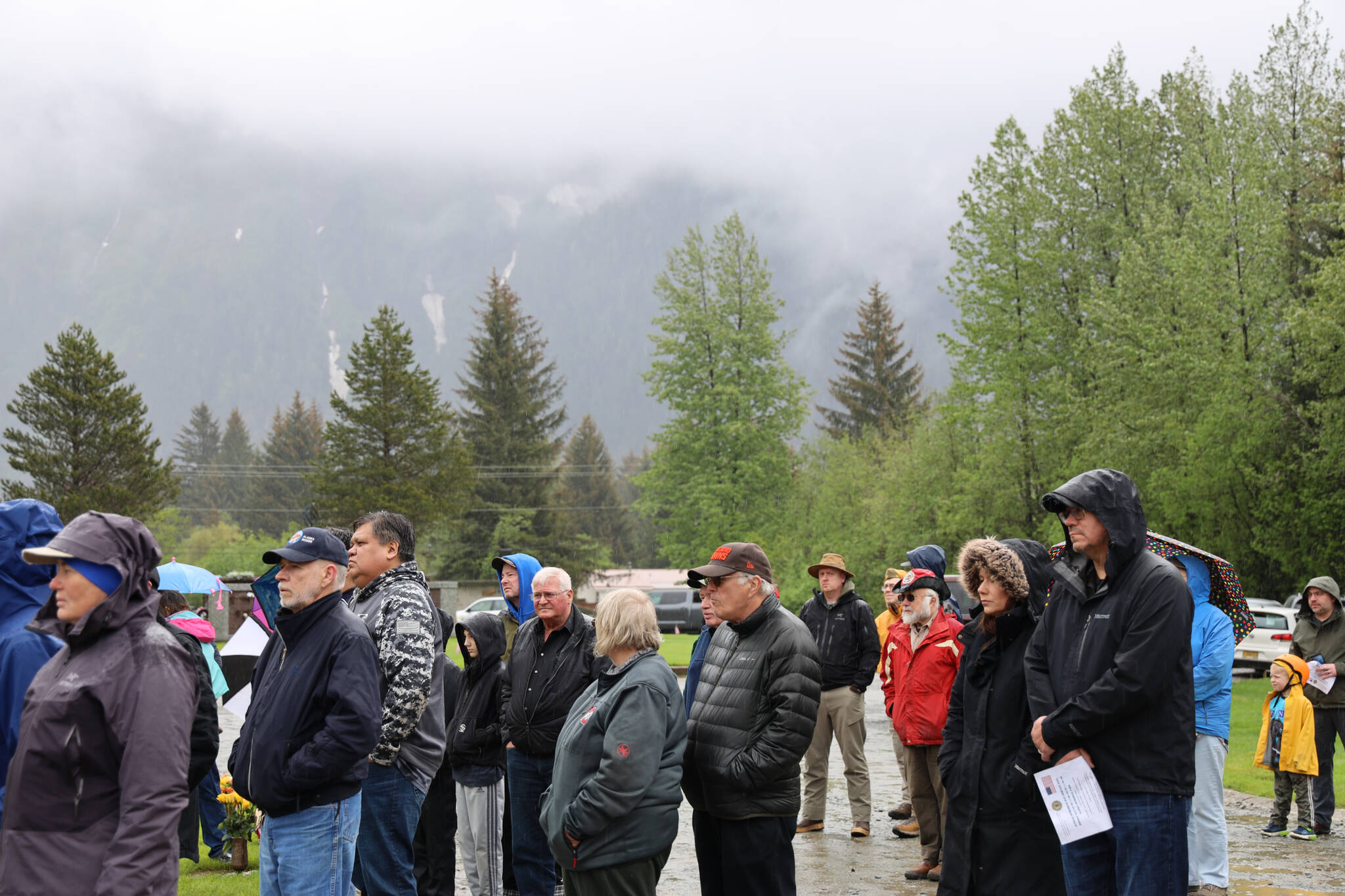 Dozens of Juneau residents and veterans stand in silence at Alaskan Memorial Park as the rain poured down for a service in observance of Memorial Day on Monday morning. (Clarise Larson / Juneau Empire)