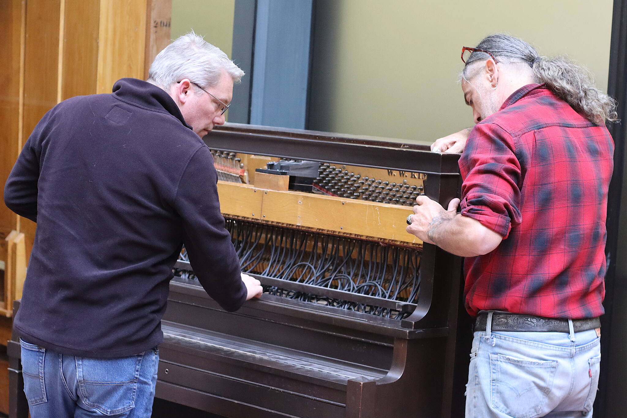 Christopher Nordwall, left, and Michael Ruppert inspect the wiring of the piano-style keyboard component of the 1928 Kimball Theatre Pipe Organ in the State Office Building on Tuesday. The component is not currently wired to the main apparatus of the instrument, so it will not be playable if performances resume as expected this month.