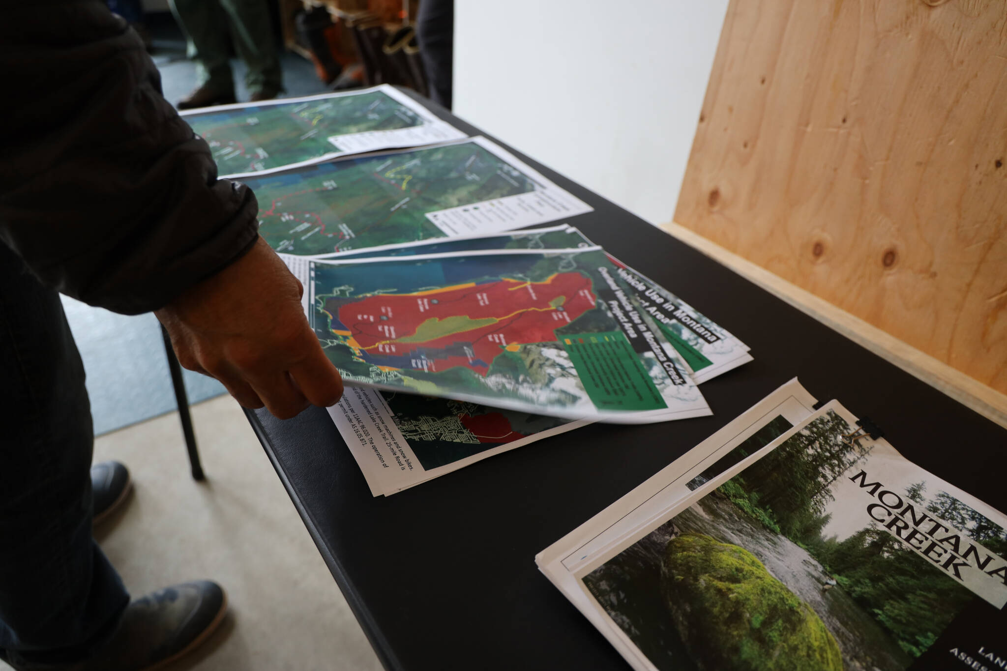 A residents grabs a print of the final Montana Creek master plan at a public meeting at the Trail Mix Inc. shop Wednesday evening. (Clarise Larson / Juneau Empire)
