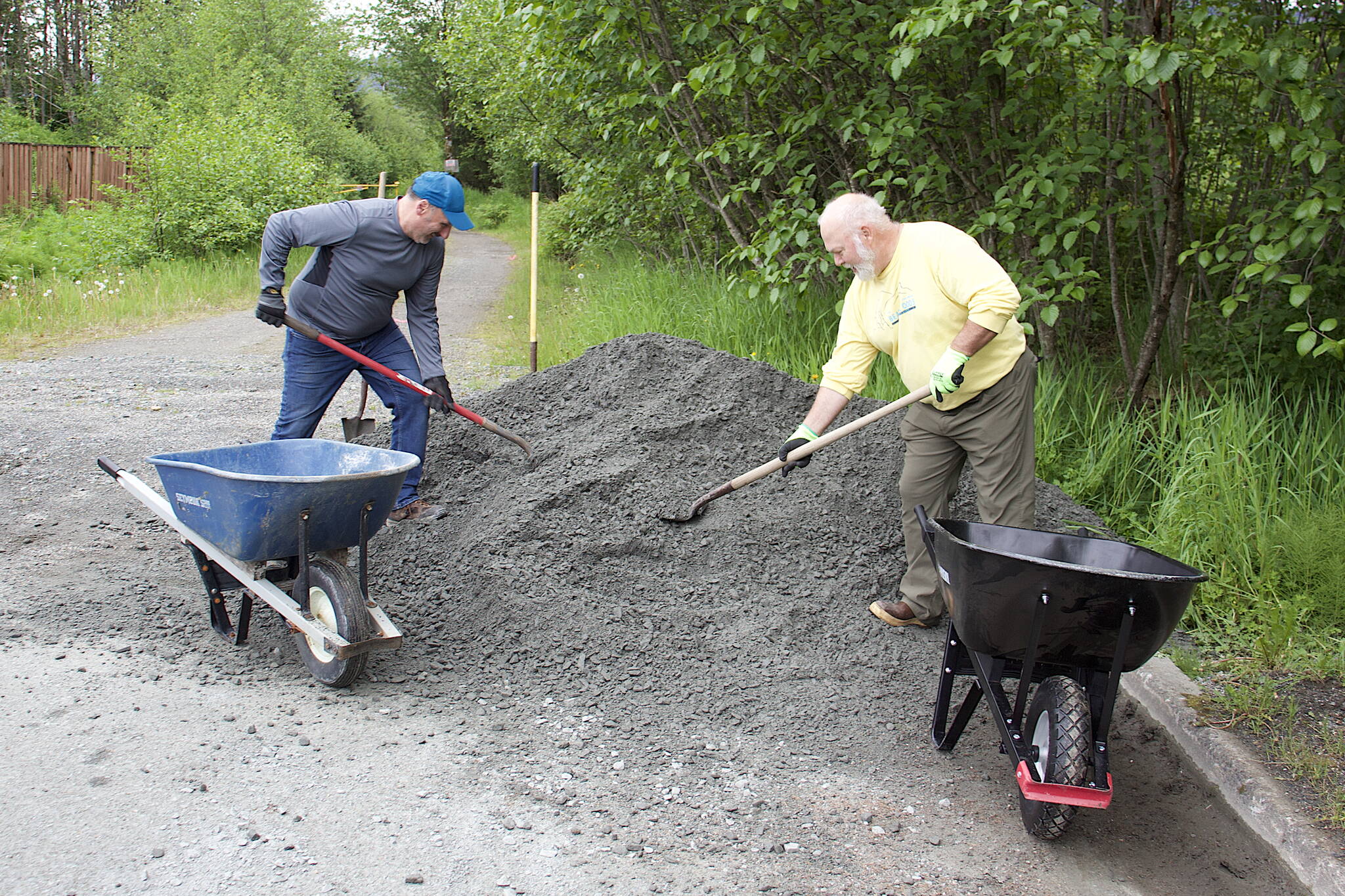 Mark Pusich, left, president of Trail Mix, and Ron Bressette, the non-profit group’s vice president, shovel gravel into wheelbarrows so it can be spread on the Kingfisher Pond Loop Trail on Saturday. The gravel is a special type that expands and retains its shape during wet weather, thus preventing washouts. (Mark Sabatini / Juneau Empire)