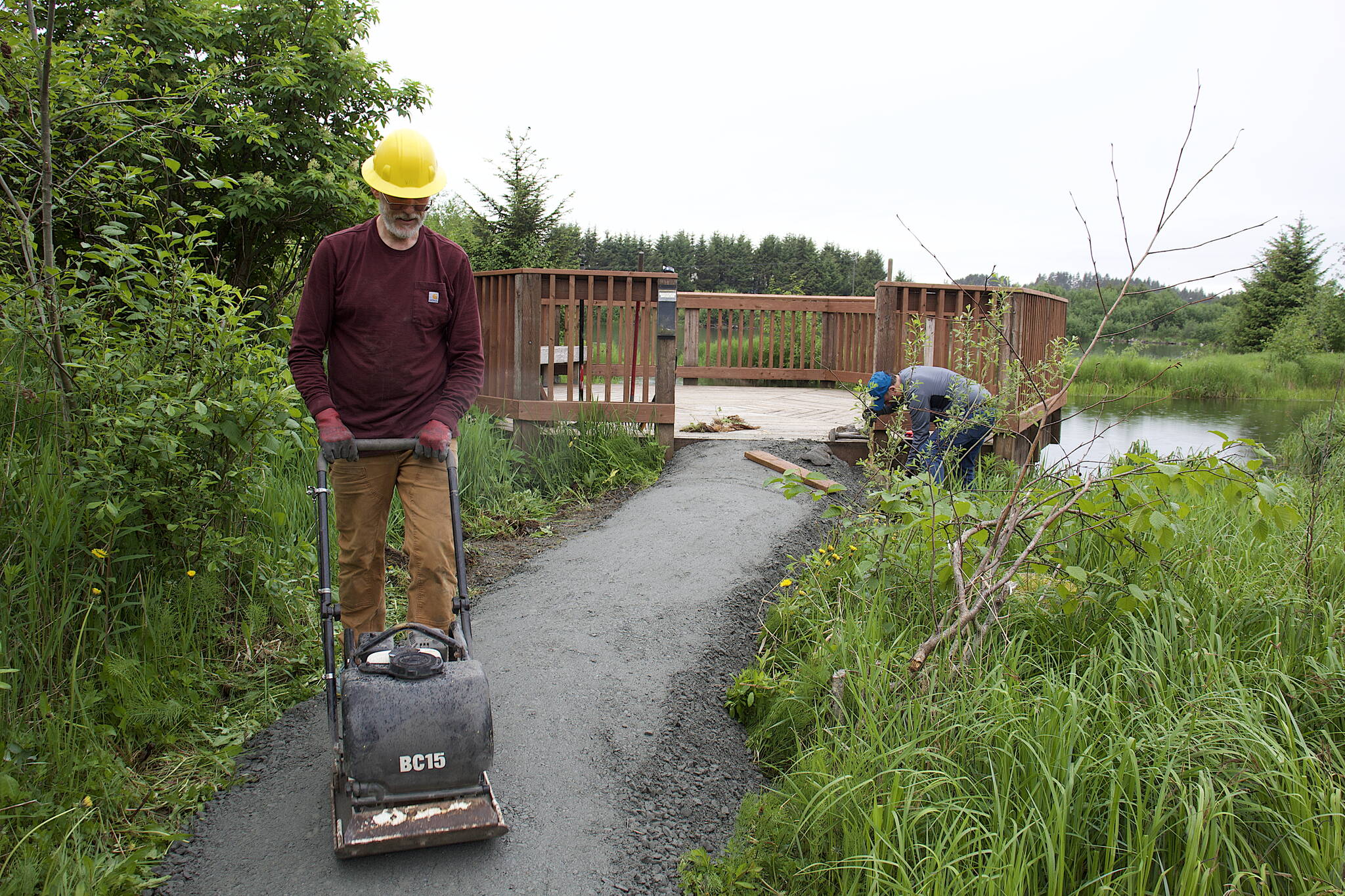 Chris Meade, a board member of Trail Mix and Juneau resident since 1991, uses a vibrating plate compactor to compress gravel leading to a viewing platform along the Kingfisher Pond Loop Trail on Saturday. (Mark Sabatini / Juneau Empire)