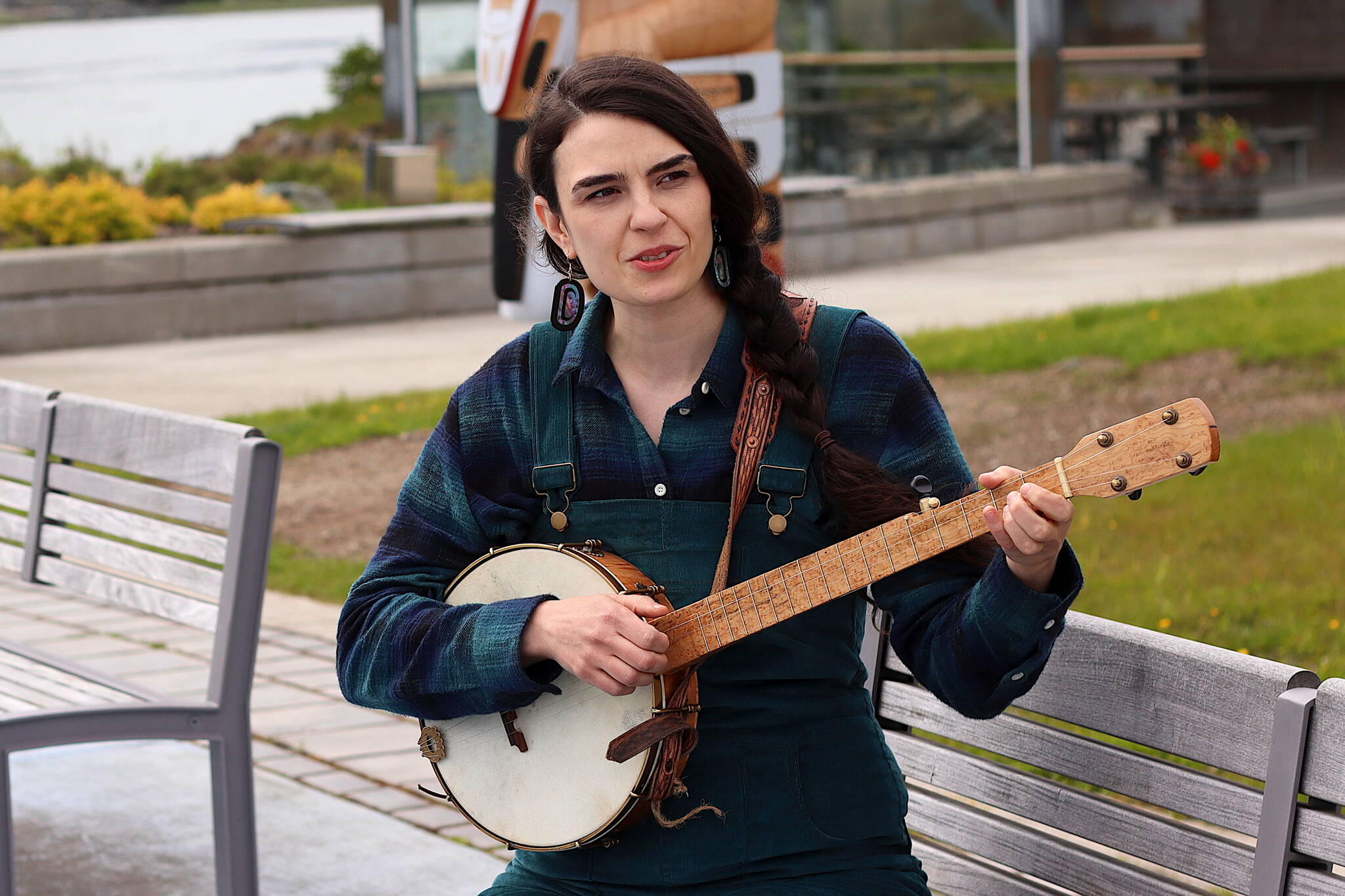 Annie Bartholomew plays a song from her upcoming debut album “Sisters of White Chapel” on a clawhammer banjo on a bench at Mayor Bill Overstreet Park on Thursday. The longtime local folk musician said she learned the instrument specifically for the project, and both the character of the instrument and women who played it during the Klondike Gold Rush helped inspire the mostly original songs she performs on the album. (Mark Sabbatini / Juneau Empire)