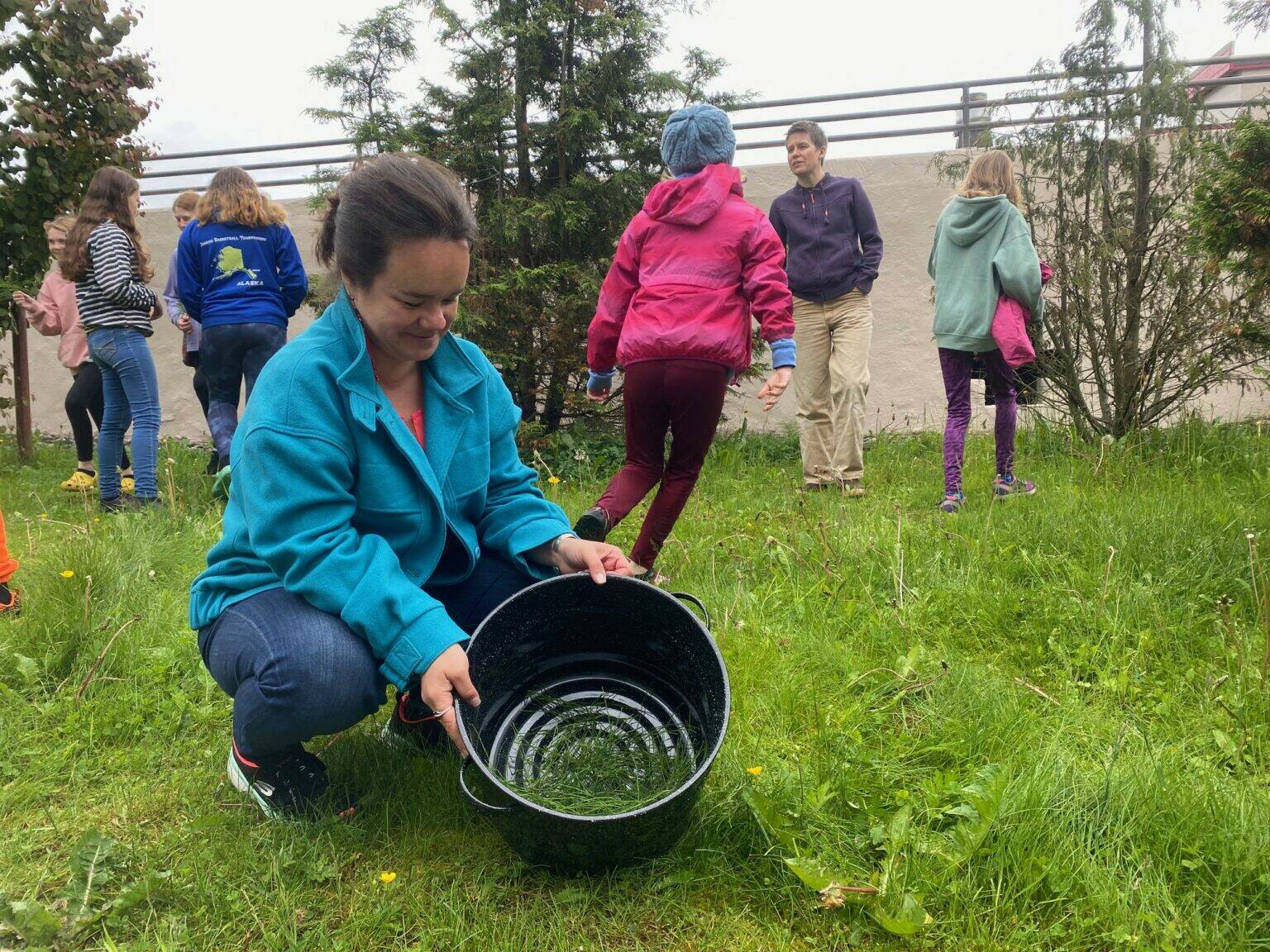 Weaver and textile artist Lily Hope shows a group of students how to forage for horsetails Saturday near the Alaska State Museum in Juneau. They boiled the plants to make a natural dye. (Photo by Claire Stremple/Alaska Beacon)