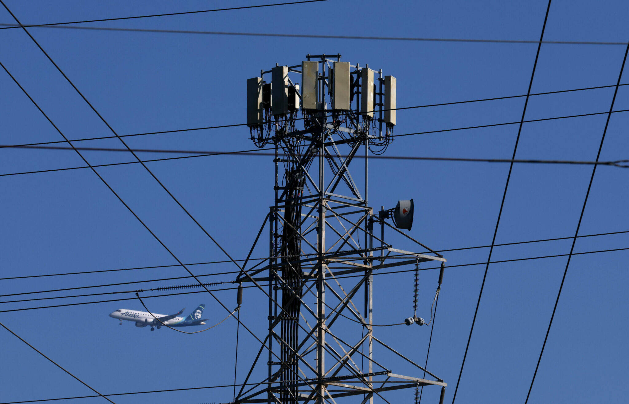 An Alaska Airlines plane flies by a cellular tower. (Photo by Justin Sullivan/Getty Images)