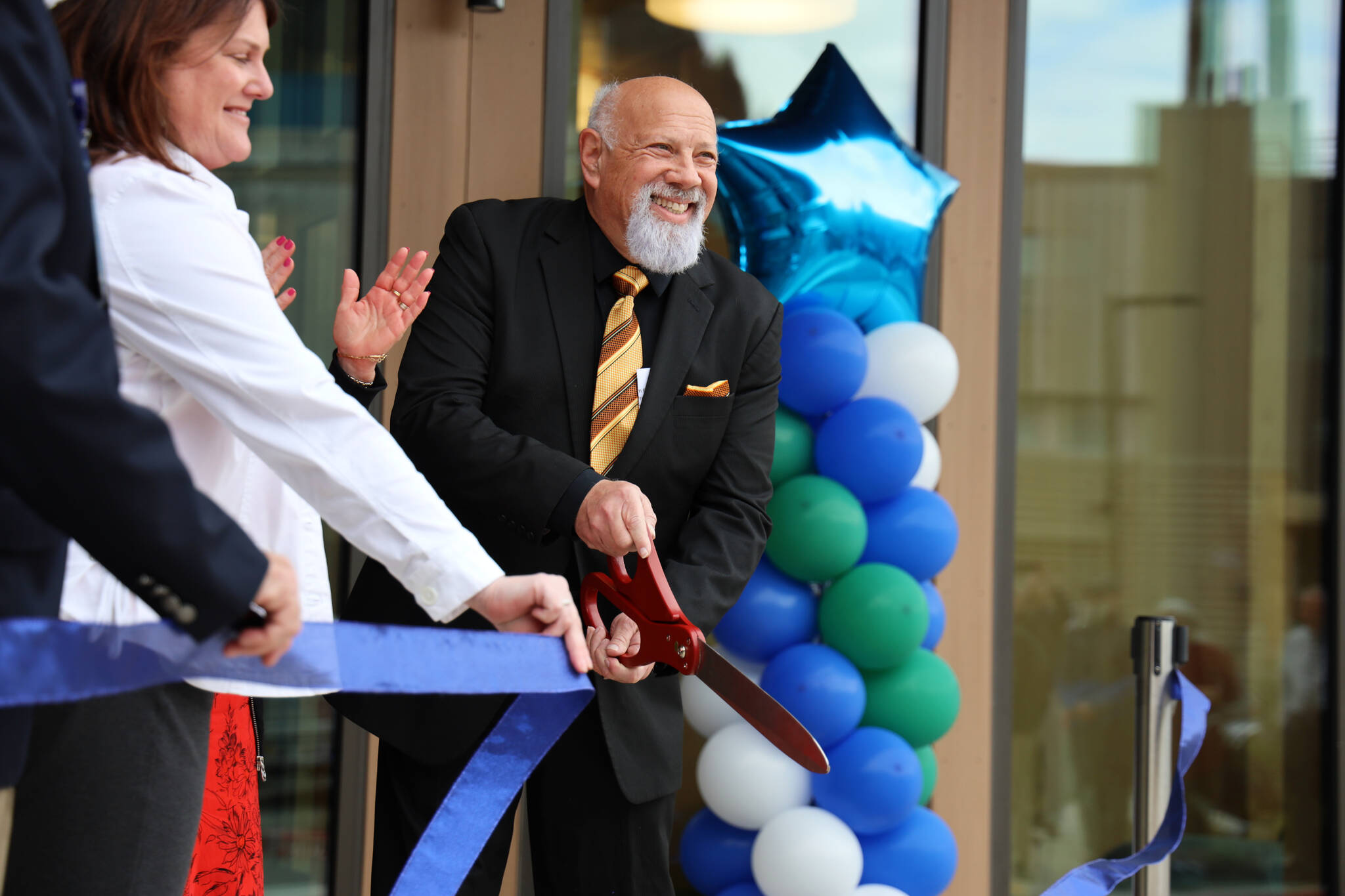 Bartlett Regional Hospital Board President Kenny Solomon-Gross cuts a ribbon in front of the doors to the hospital’s new Aurora Behavioral Health Center unveiled Wednesday evening. (Clarise Larson / Juneau Empire)