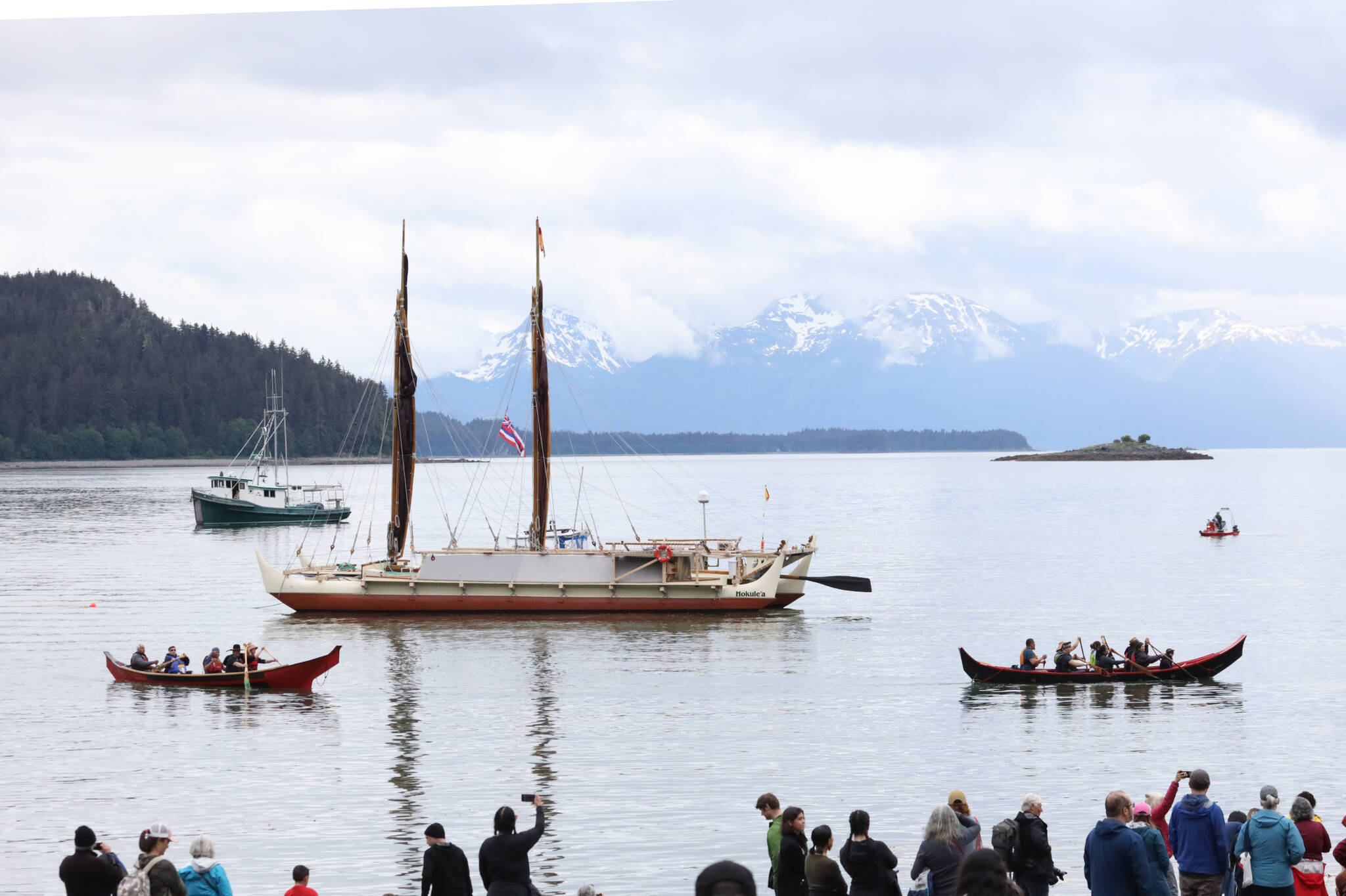 A crowd gathers at the shore of Auke Bay as the Hōkūle‘a, a double-hulled and wind-powered traditional Polynesian voyaging canoe, arrives in Juneau on Saturday afternoon for a welcoming ceremony. (Clarise Larson / Juneau Empire)