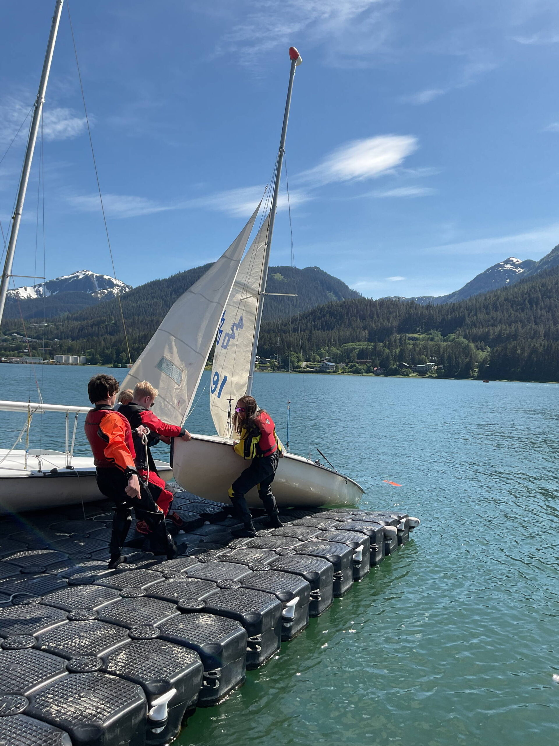 From left to right, Kaia Mangaccat, 13, Lua Mangaccat, 15, Sigrid Eller, 13, and Adrian Whitney, 19, pull a boat out of the water after a sailing lesson in Gastineau Channel this week. (Therese Pokorney / Juneau Empire)