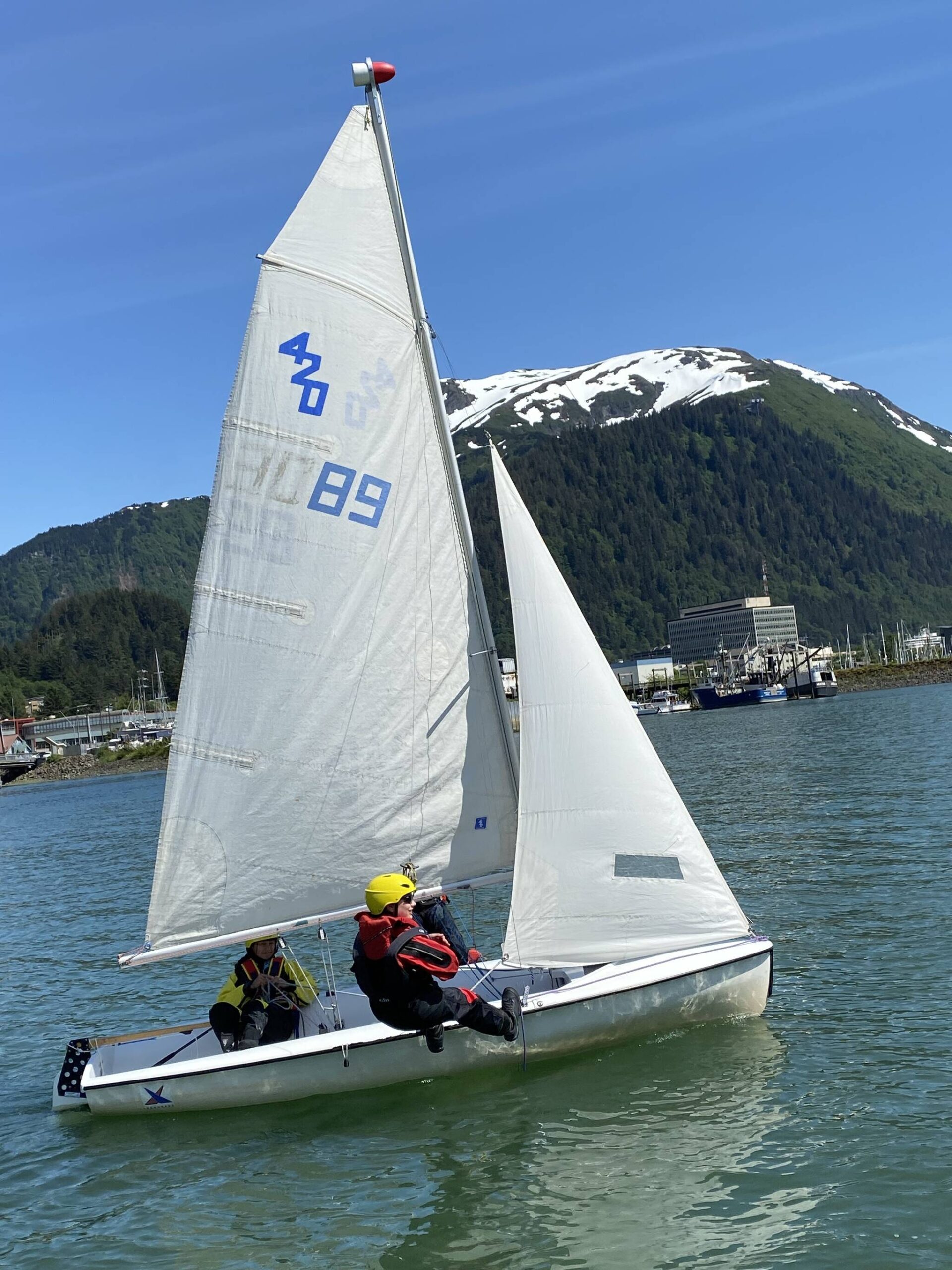 Jack Adams, 15, Lua Mangaccat, 15, and Sigrid Eller, 13, sail within view of downtown Juneau and the surrounding mountains during a Juneau Youth Sailing course this week. (Photo by Adrian Whitney)
