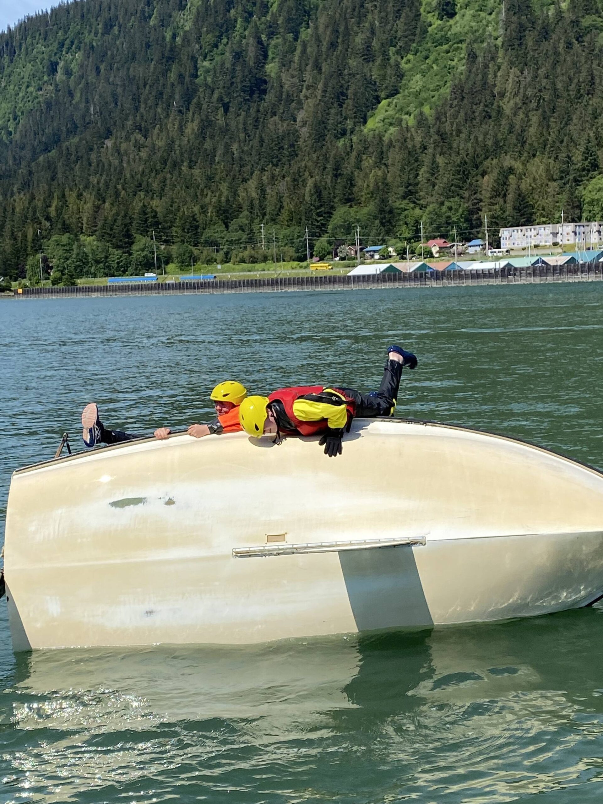 Lauren Stichert, 16, and Angus Andrews, 14, climb aboard a capsized sailboat during a sailing lesson this week in Gastineau Channel. (Photo by Adrian Whitney)