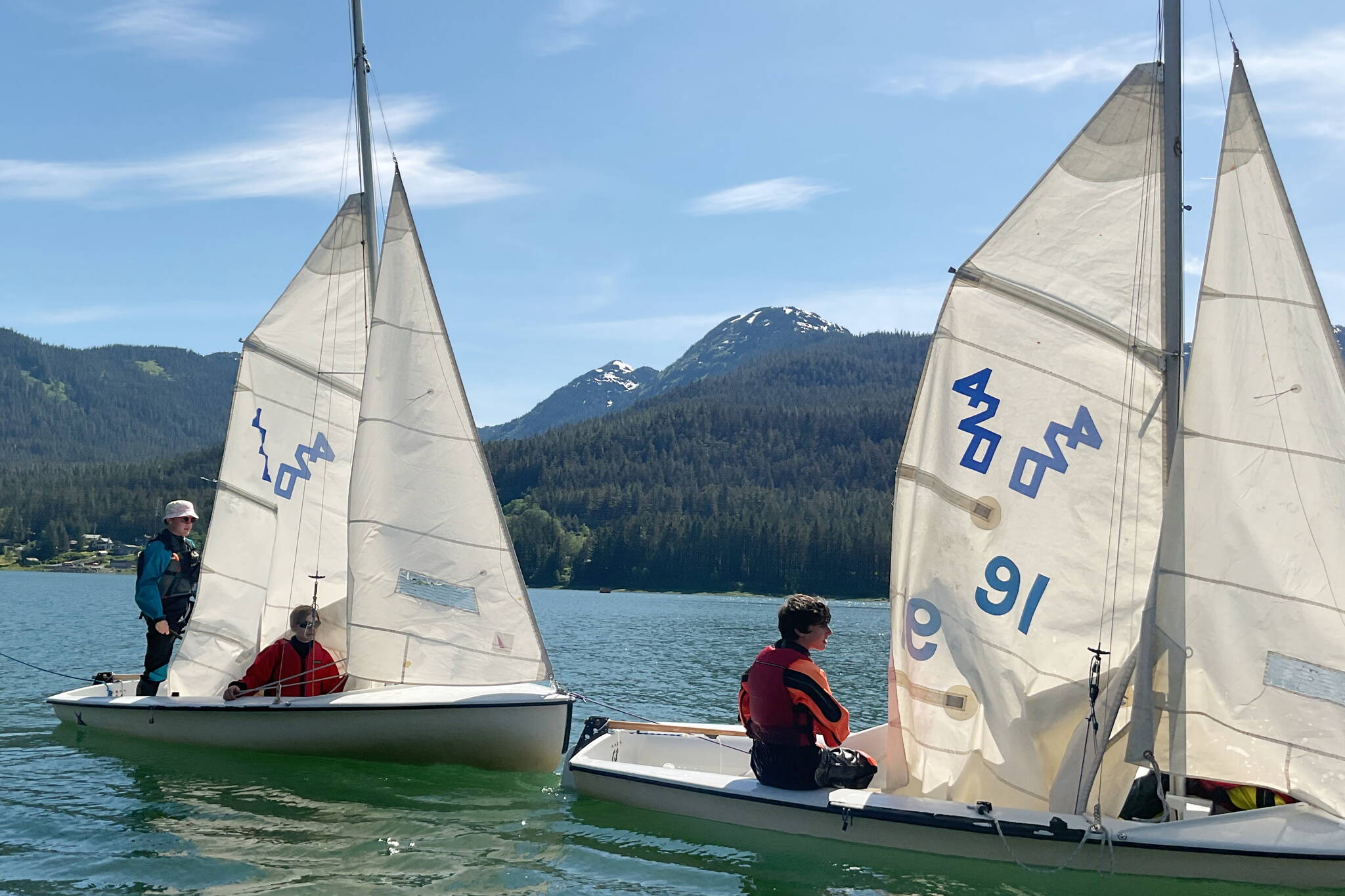 Brendan West, 17, left, and Jack Adams, 15, guide one sailboat while Wesley Torgerson, 16, helps guide another to the dock during a Juneau Youth Sailing course this week. (Therese Pokorney / Juneau Empire)