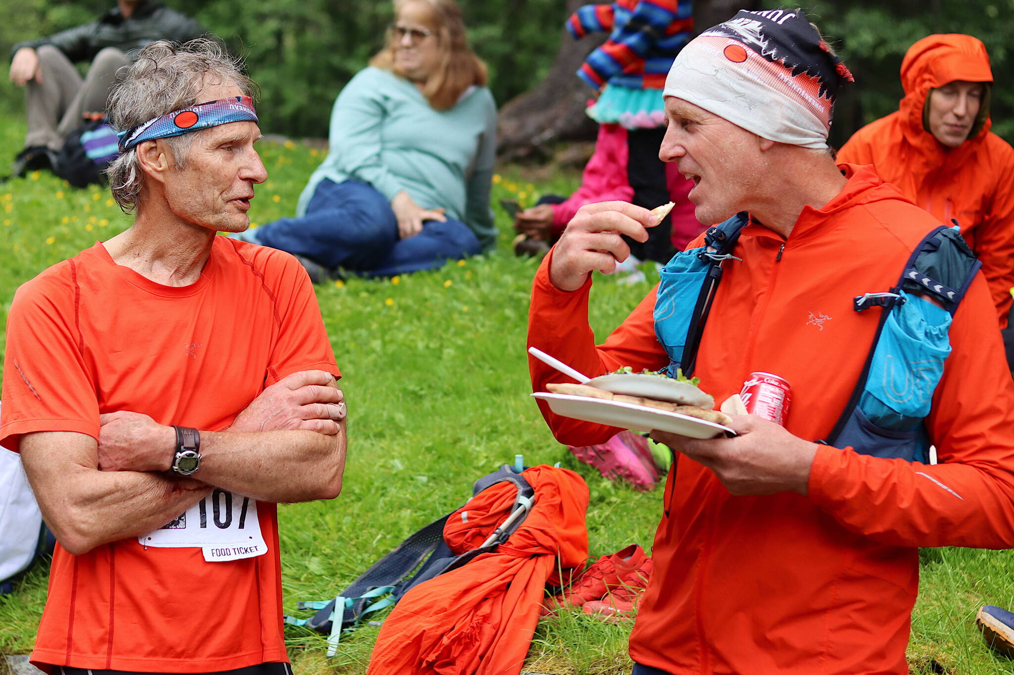 Alex Andrews, right, refuels with pizza and salad while talking with Dan Rondeau after the Juneau Ridge Race at Cope Park on Sunday. (Mark Sabbatini / Juneau Empire)