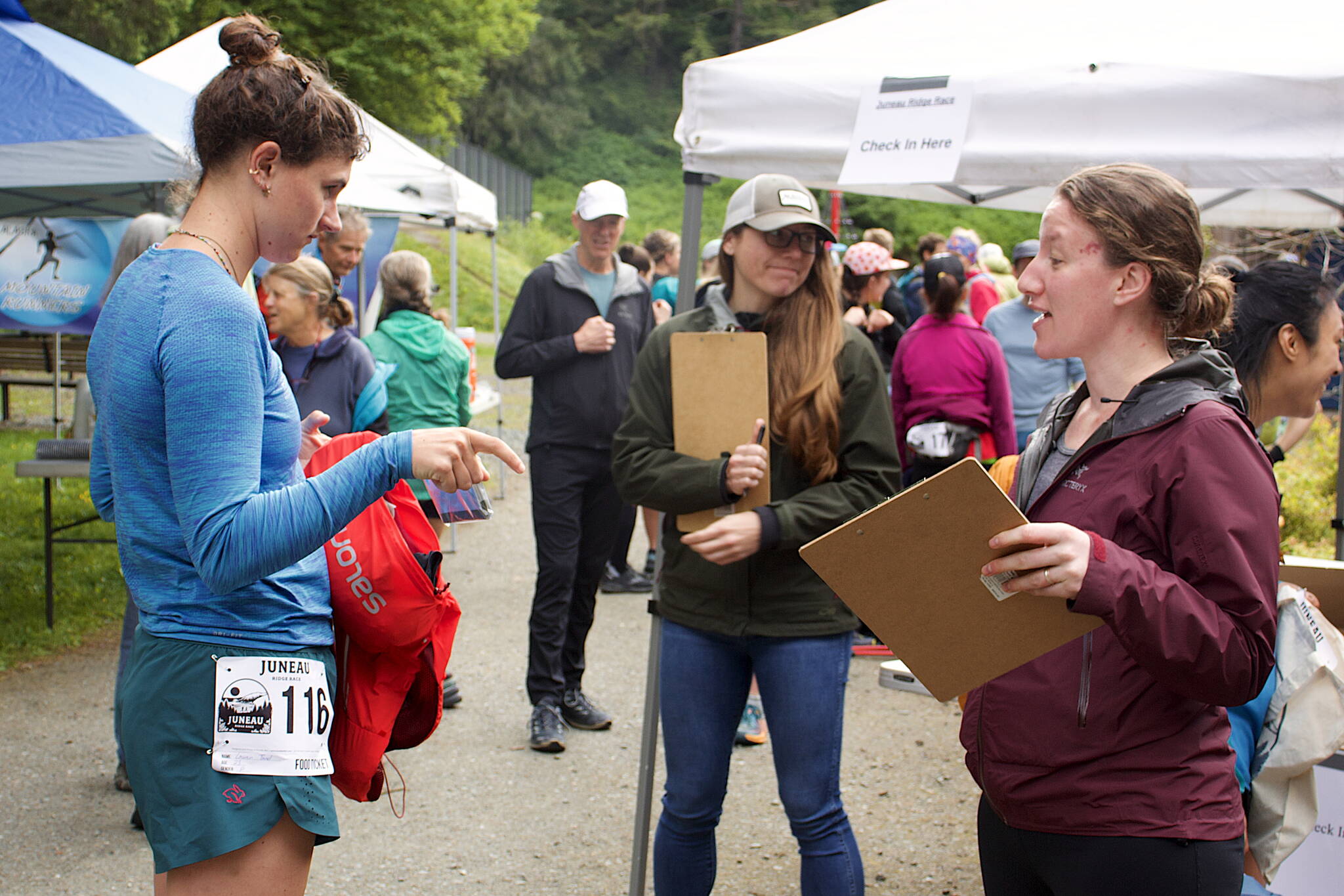 Lauren Tanel, left, shows an emergency space blanket to Sarah Lucas during an equipment check before the Juneau Ridge Race on Sunday at Cope Park. Participants in the race were also required to carry a jacket, long-sleeve shirt, hat, gloves, water and food. (Mark Sabbatini / Juneau Empire)