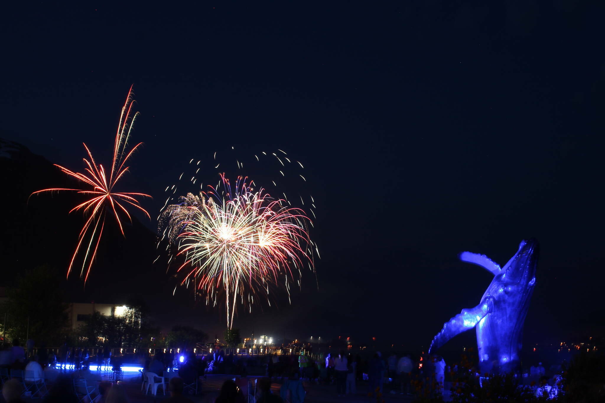 Locals gathered for a whale of a time near “Tahku,” the whale sculpture under shimmering lights and loud booms for the annual firework display over Gastineau Channel in 2022. (Clarise Larson / Juneau Empire File)
