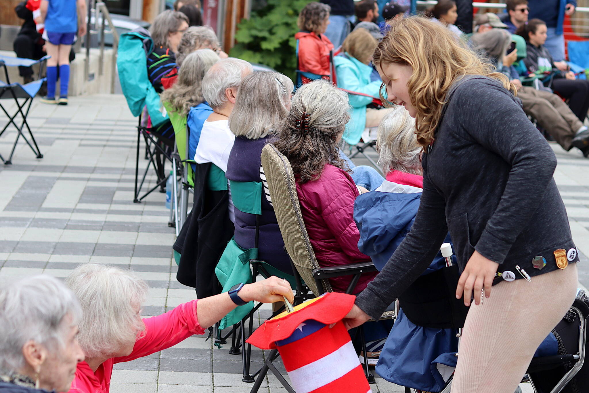 Gabi Williams collects donations on behalf of Juneau Community Bands from people in the audience during a concert by the Juneau Volunteer Marching Band on Sunday at Sealaska Heritage Plaza. (Mark Sabbatini / Juneau Empire)